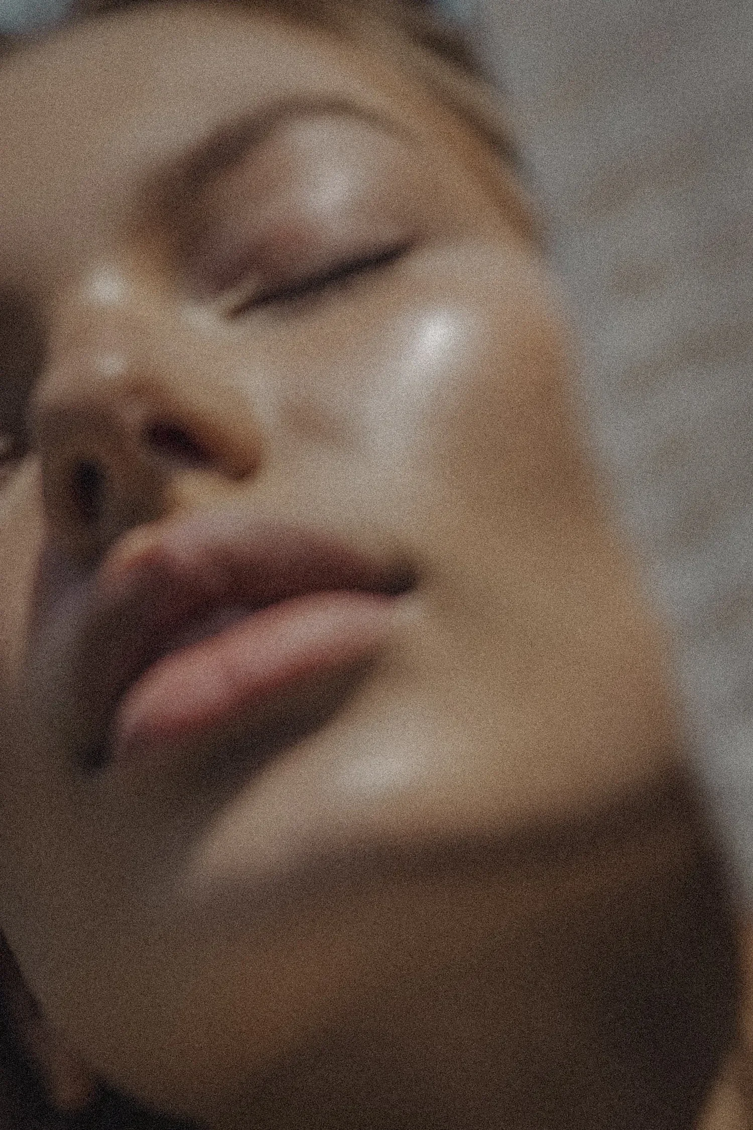 Close-up of a person's face with eyes closed, showing makeup and full lips.