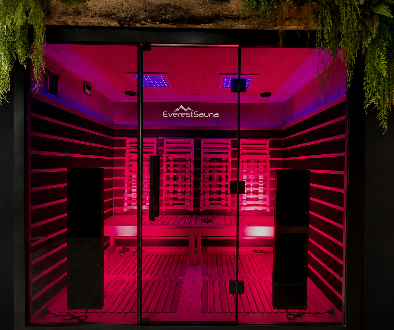 Inside a modern sauna with pink lighting, wooden benches, and a sign reading 'Everest Sauna' on the wall.