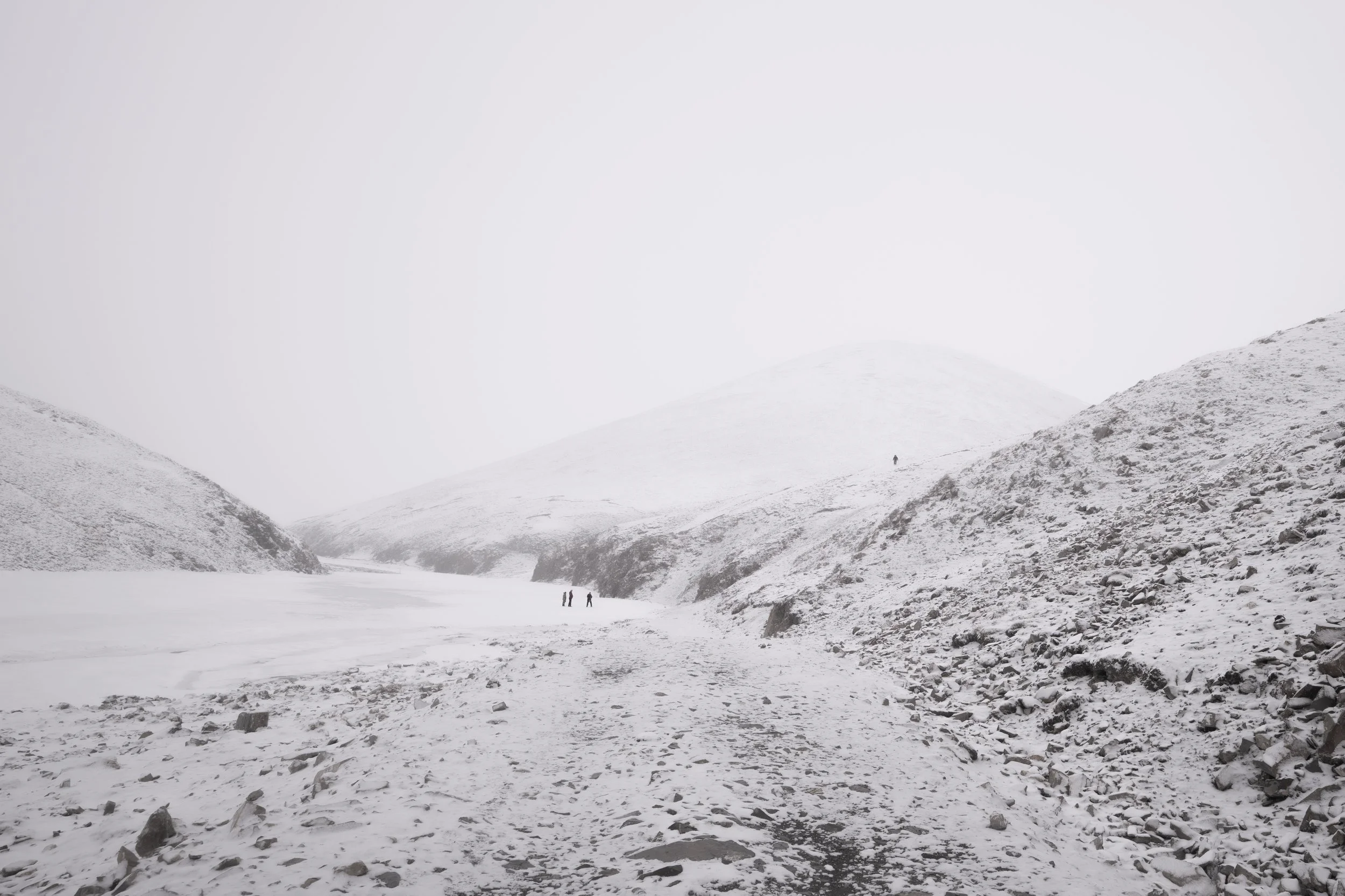 In the stormy and snowy landscape of Yushu, Sanjiangyuan, the tiny figures of guides scanning for wildlife create a beautiful and serene scene.