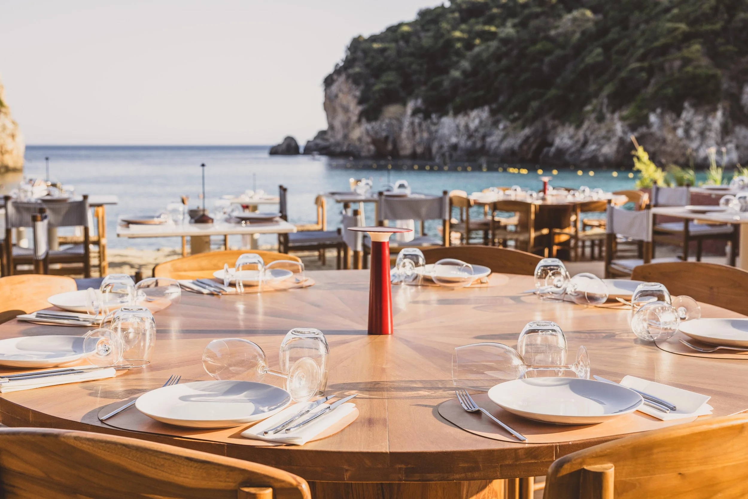 Beachfront dining in Paleokastritsa, Corfu with stunning views of the Ionian Sea and surrounding coastline.