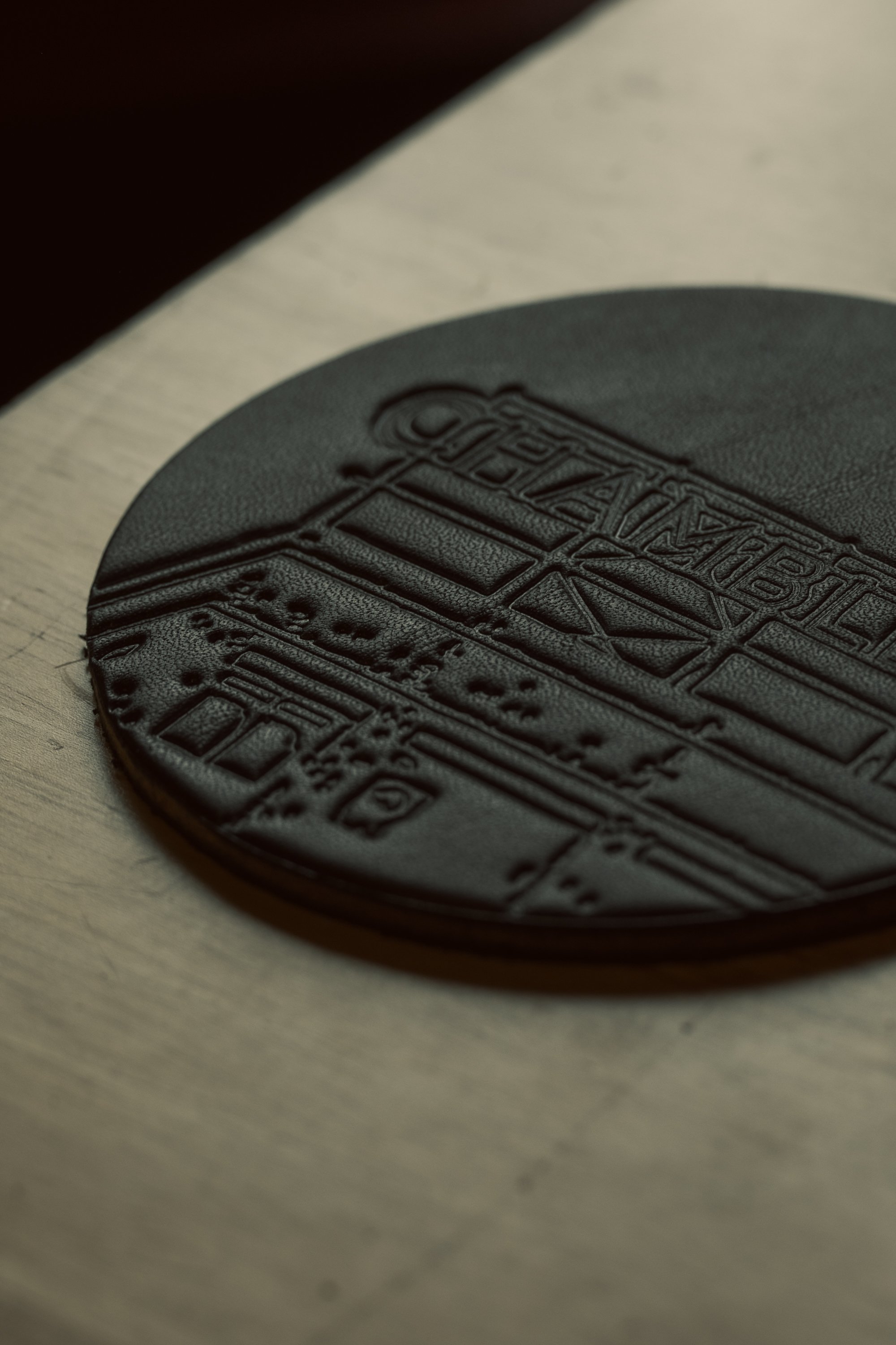 Close-up of a black circular object with embossed text and symbols, placed on a light-colored wooden surface.