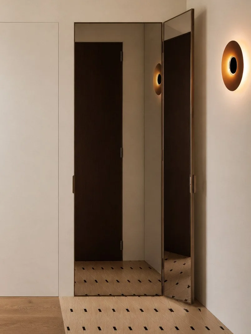 foyer with bronze mirrored wardrobe doors, amber disc wall light and inlaid timber floor