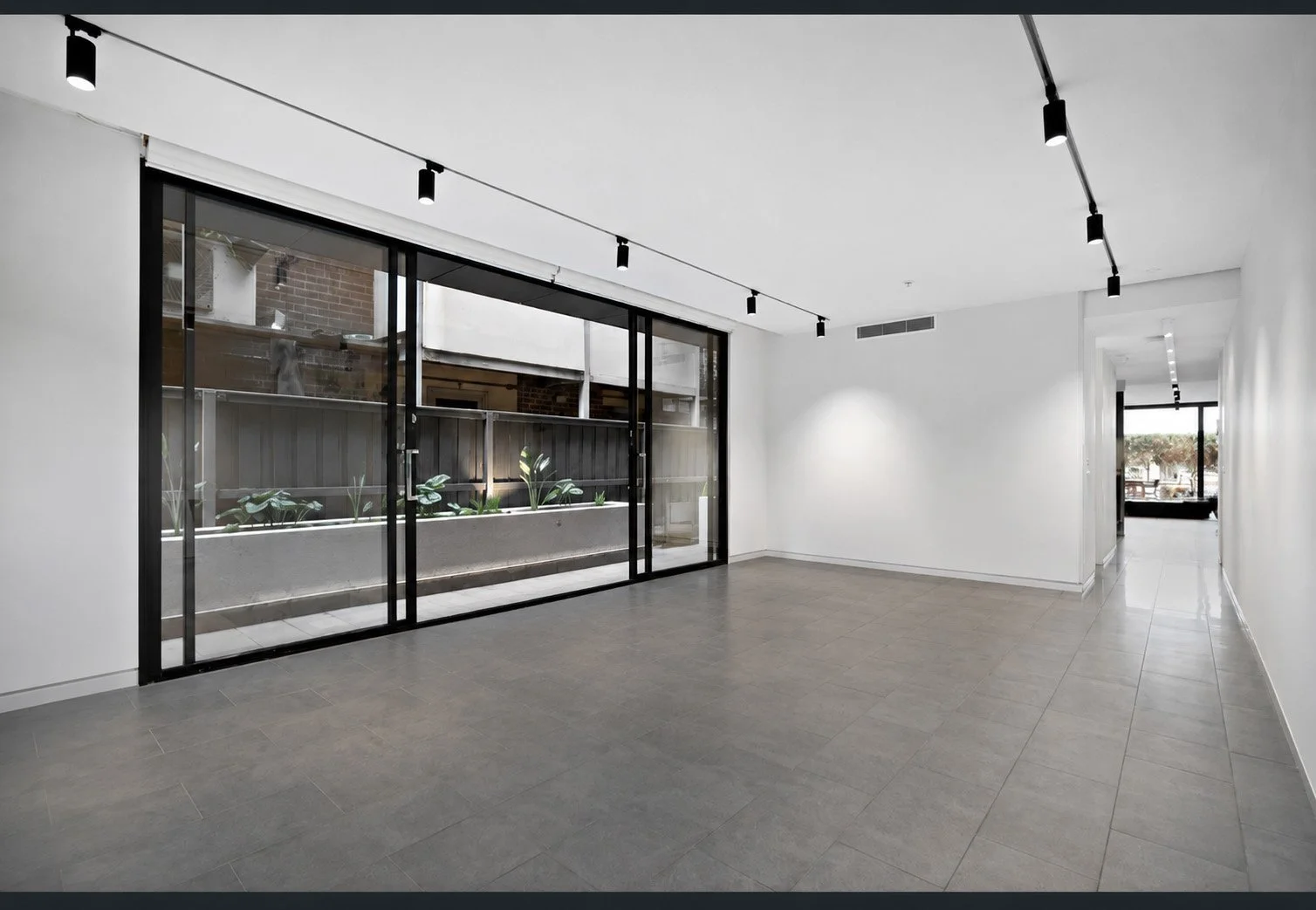 Study area before the design — grey tiled floor and black-framed sliding doors