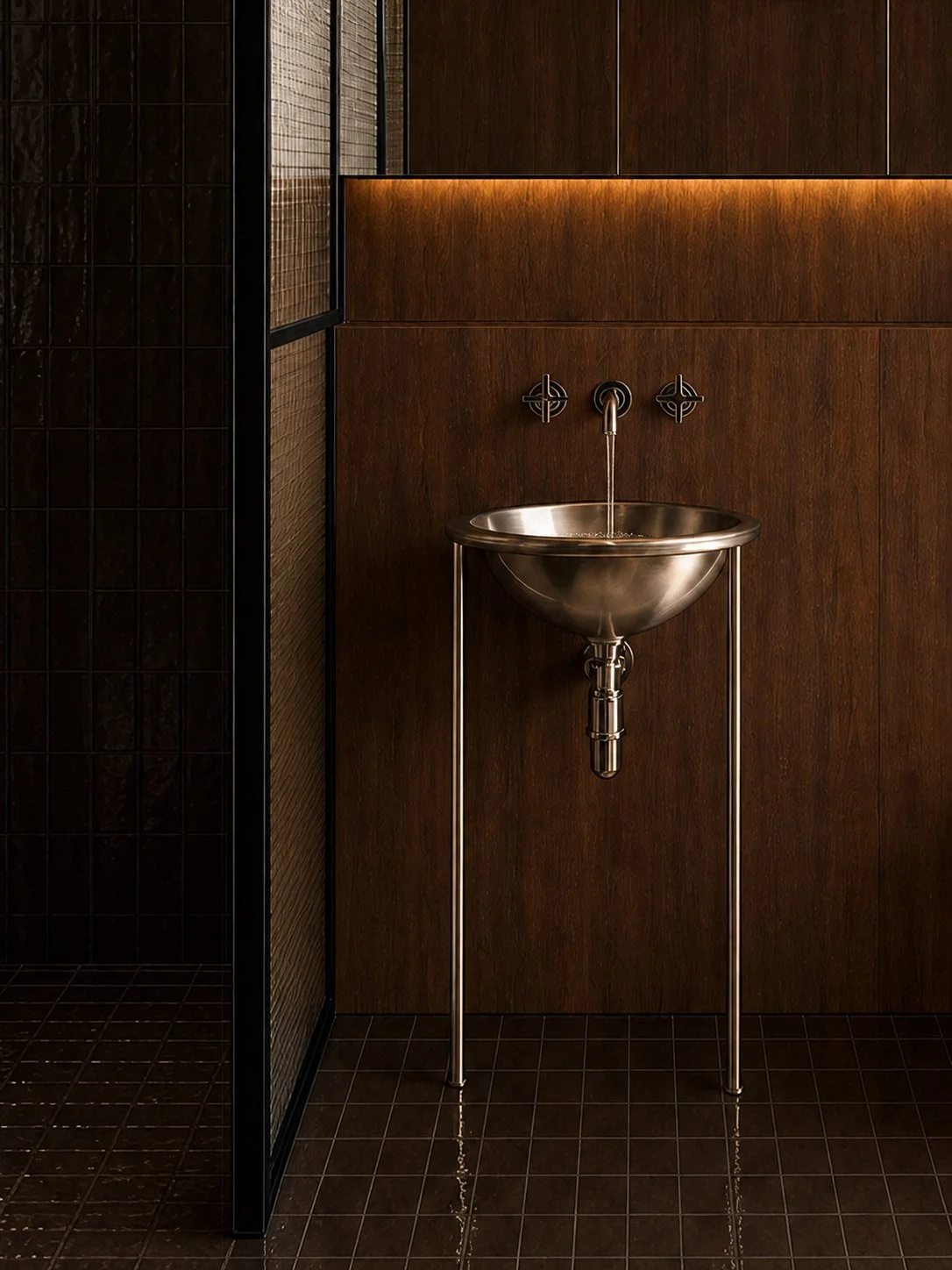 Stainless steel basin on slender legs against dark walnut and chocolate tile, behind a mesh glass steel framed screen