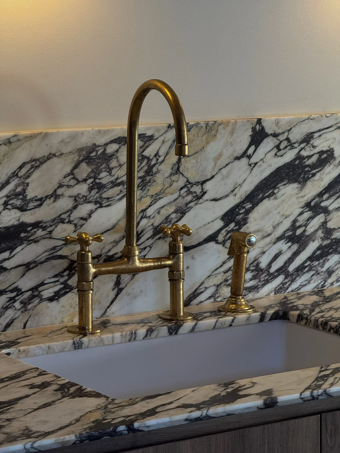 Aged brass bridge tap and spray against a Calacatta Monet splashback