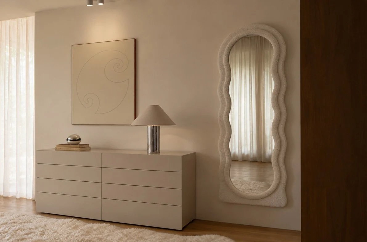 Dressing area with a wavy boucle full-length mirror, cream chest of drawers and chrome table lamp
