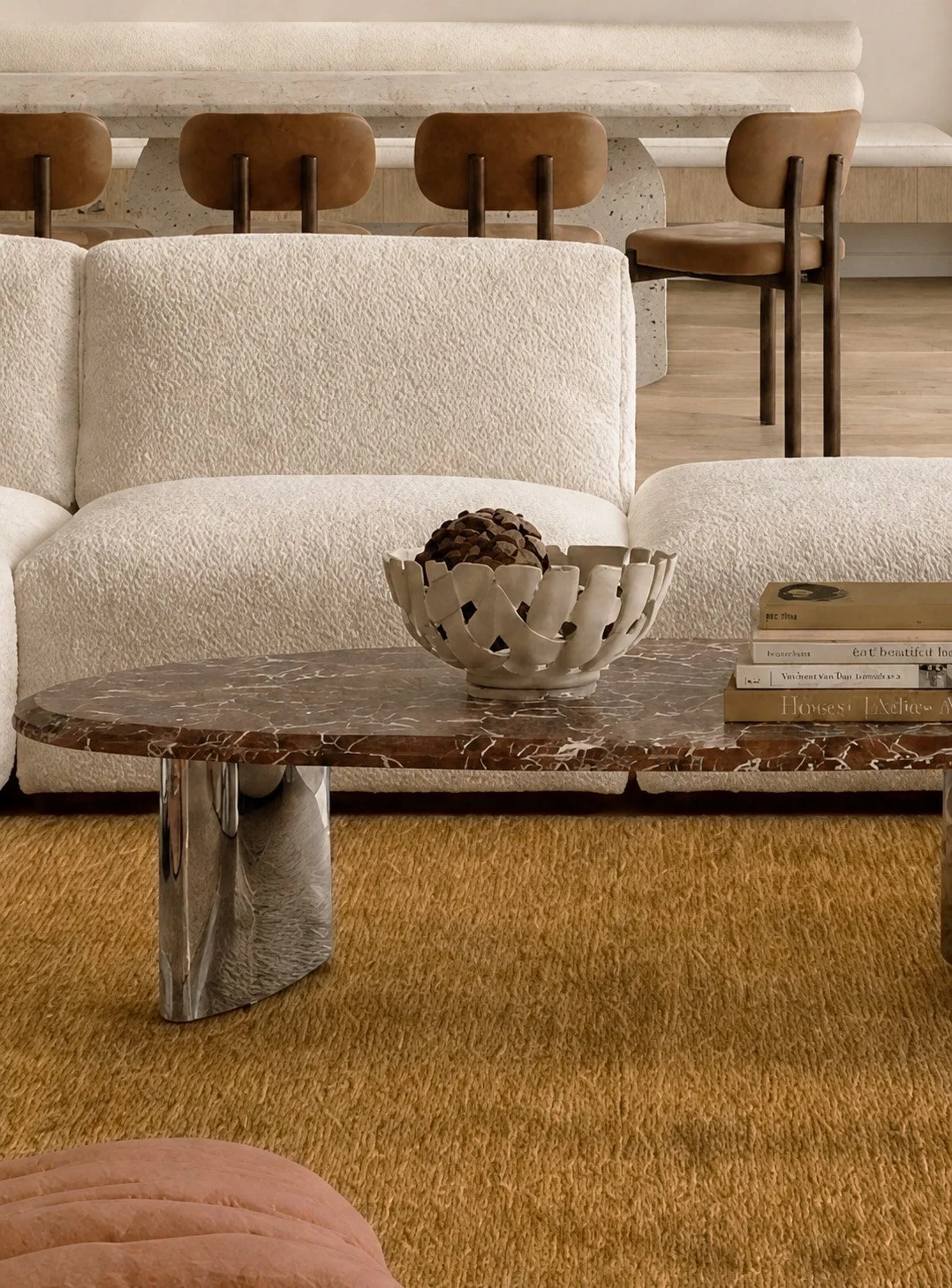 Cream boucle sofa and Rosso Levanto coffee table on an ochre rug, with the travertine dining banquette beyond