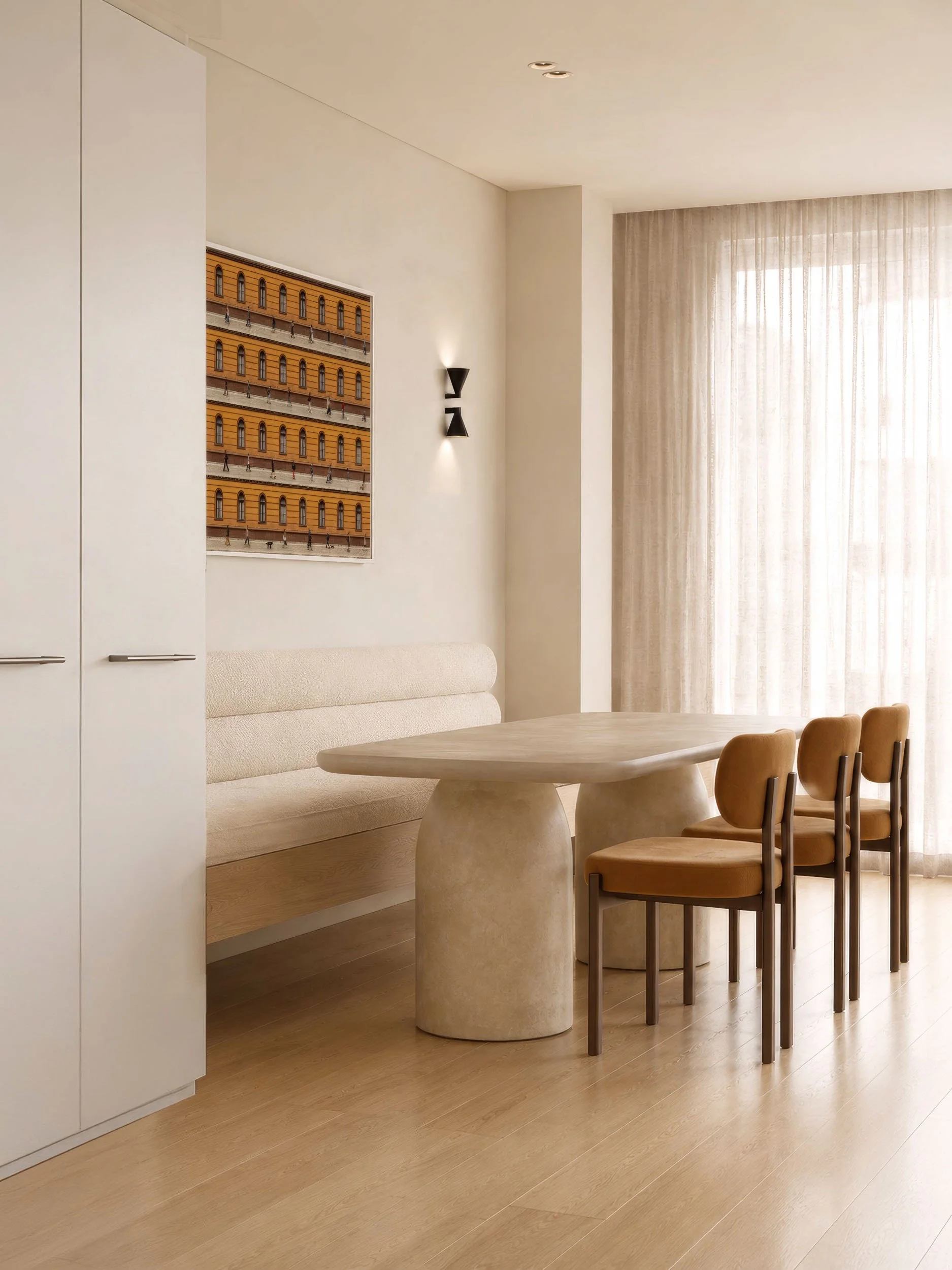 Travertine dining table and tan velvet chairs against a cream banquette and sheer curtains