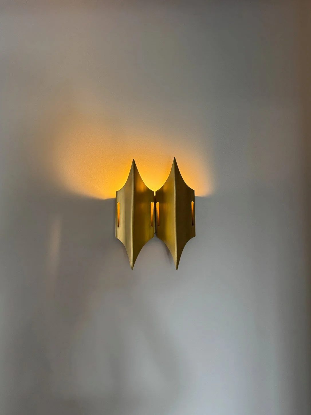 Vintage brass wall sconce throwing a pool of warm light across the wall