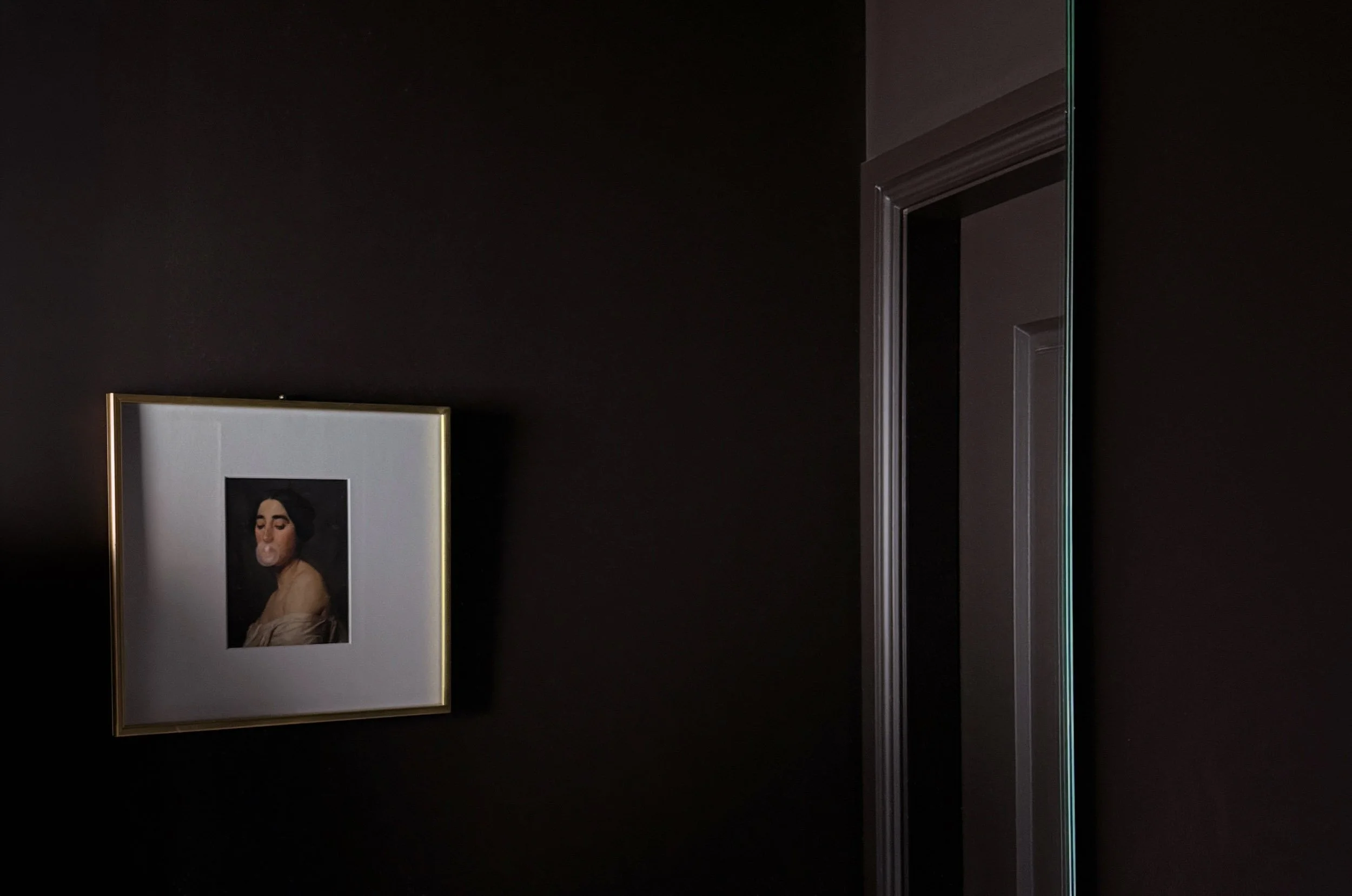 Gold-framed portrait of a woman blowing a bubblegum bubble, on a wall drenched in deep aubergine