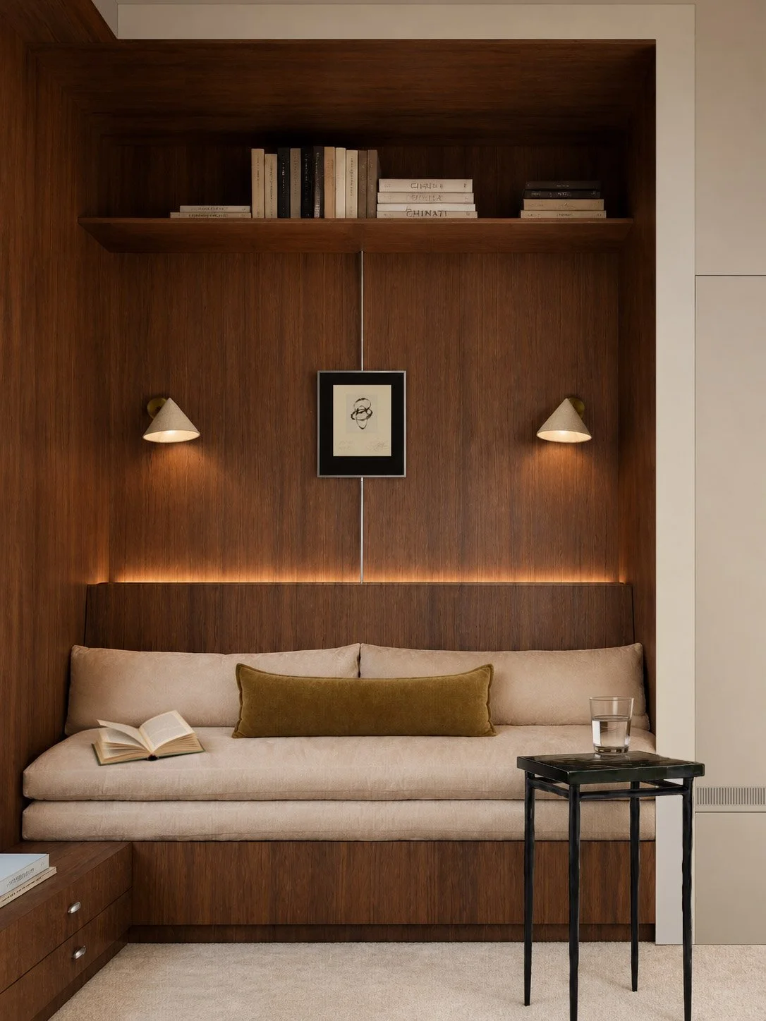 Reading nook built into walnut joinery, cream daybed with olive bolster and twin conical sconces