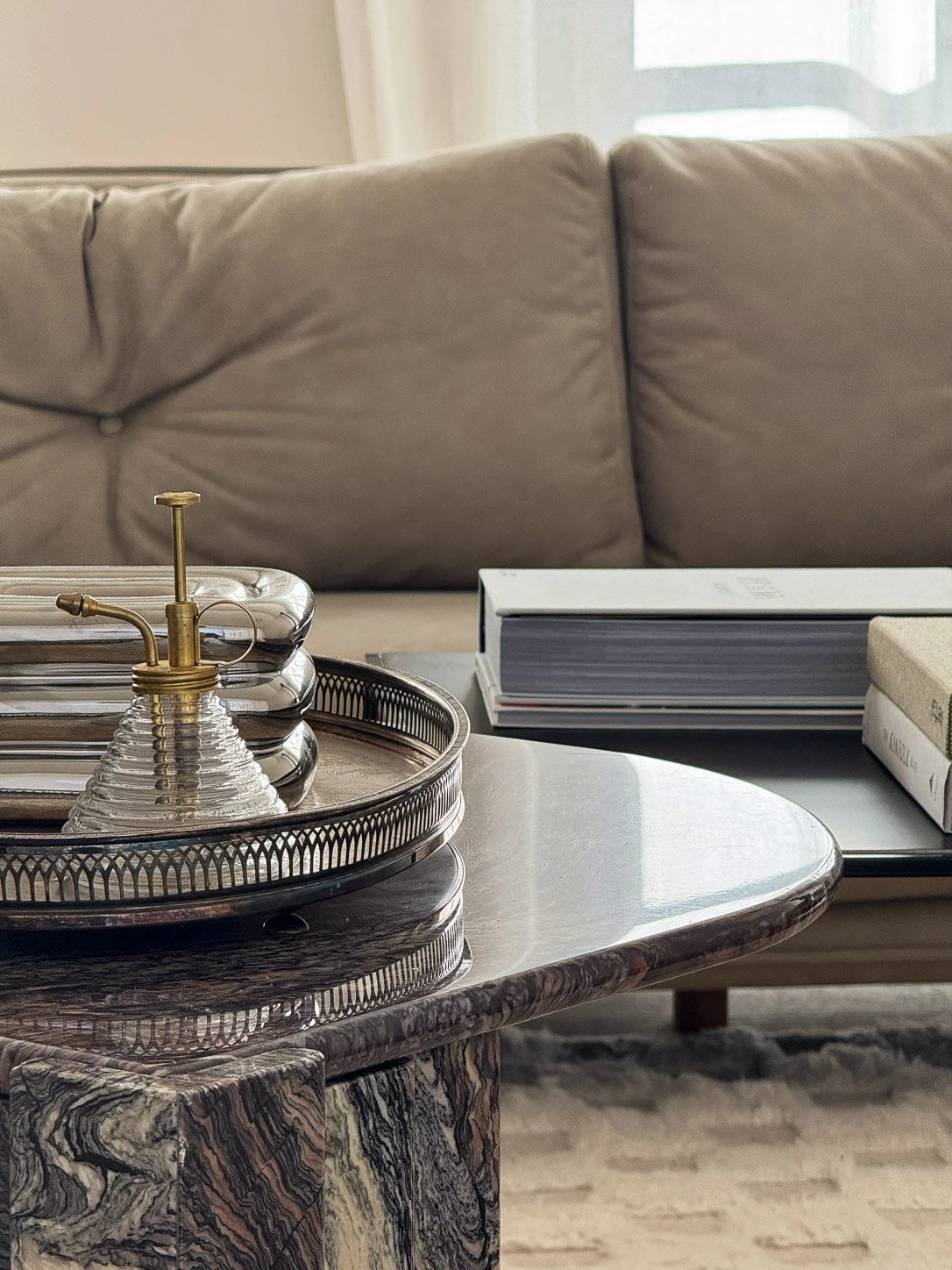 Silver gallery tray and brass plant mister on the marble coffee table