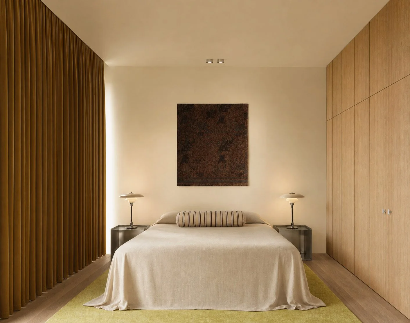 Bedroom with a full wall of mustard velvet curtains behind oak wardrobes and a batik artwork