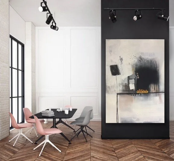 Modern conference room with five chairs around a black table, large abstract painting on a black wall, and track lighting on white ceiling in a bright space