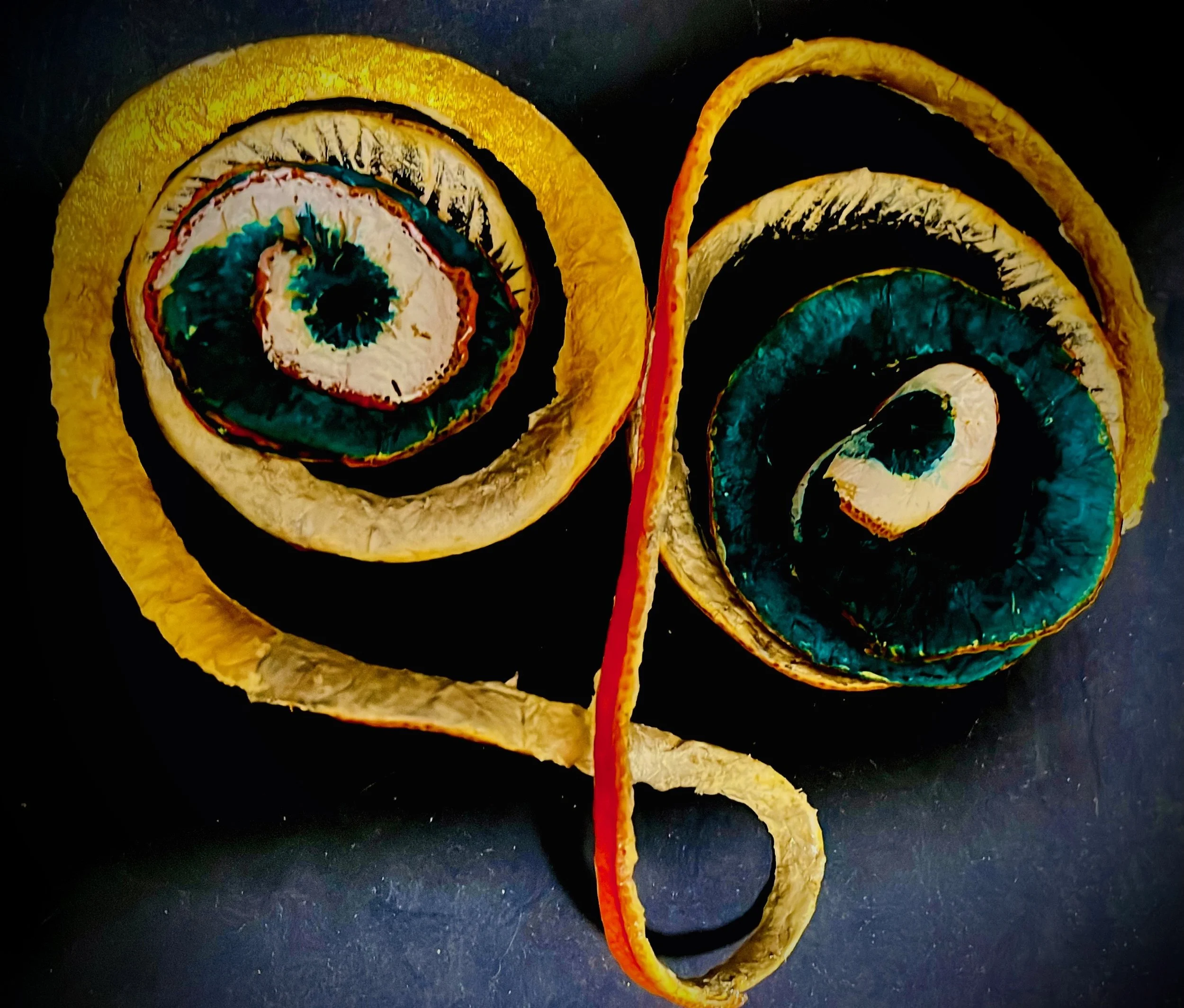 Colorful spiral-shaped citrus rind, arranged on a dark surface.