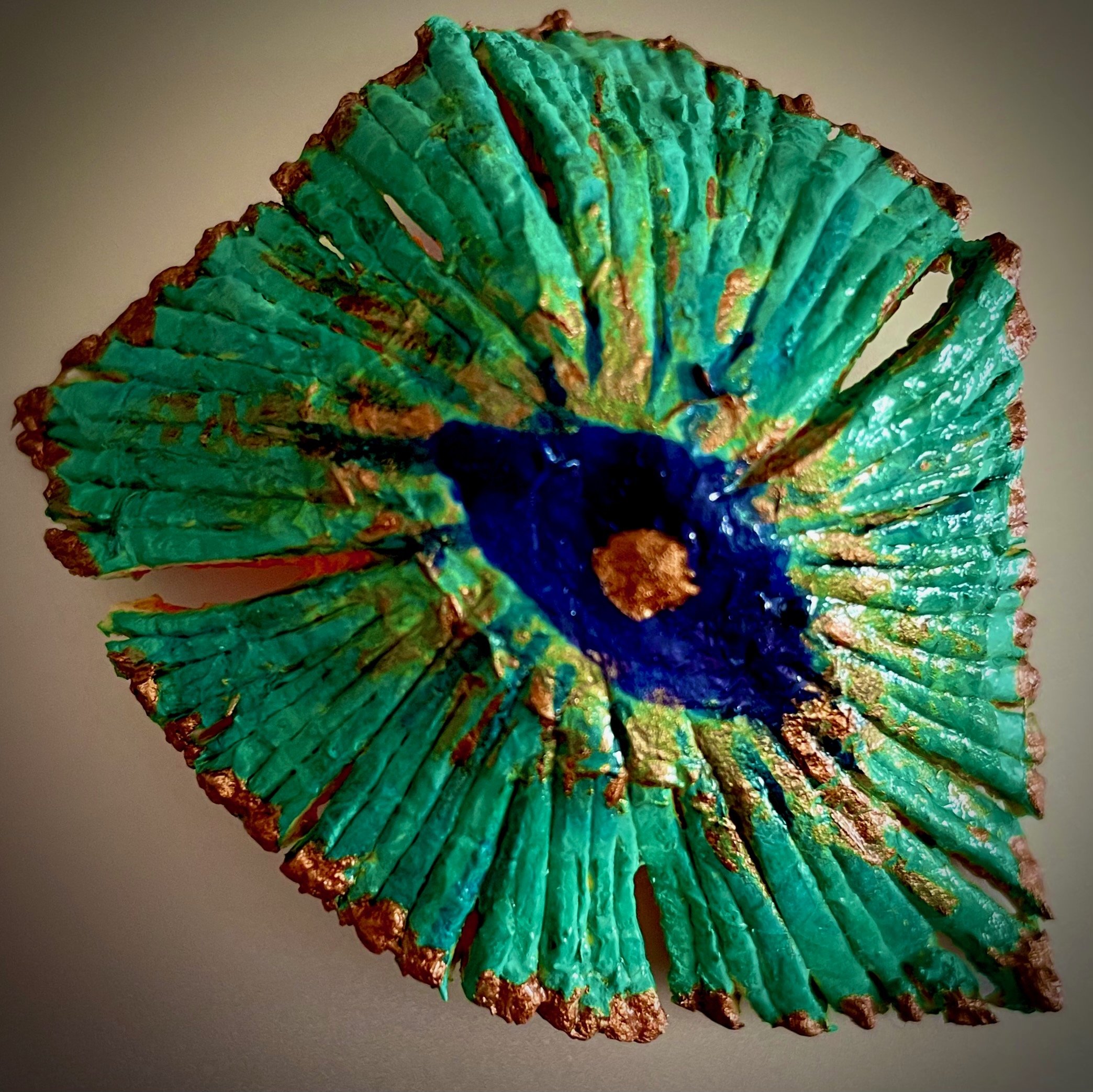 Close-up of a decorative citrus rind art piece resembling a green sea shell with gold accents.