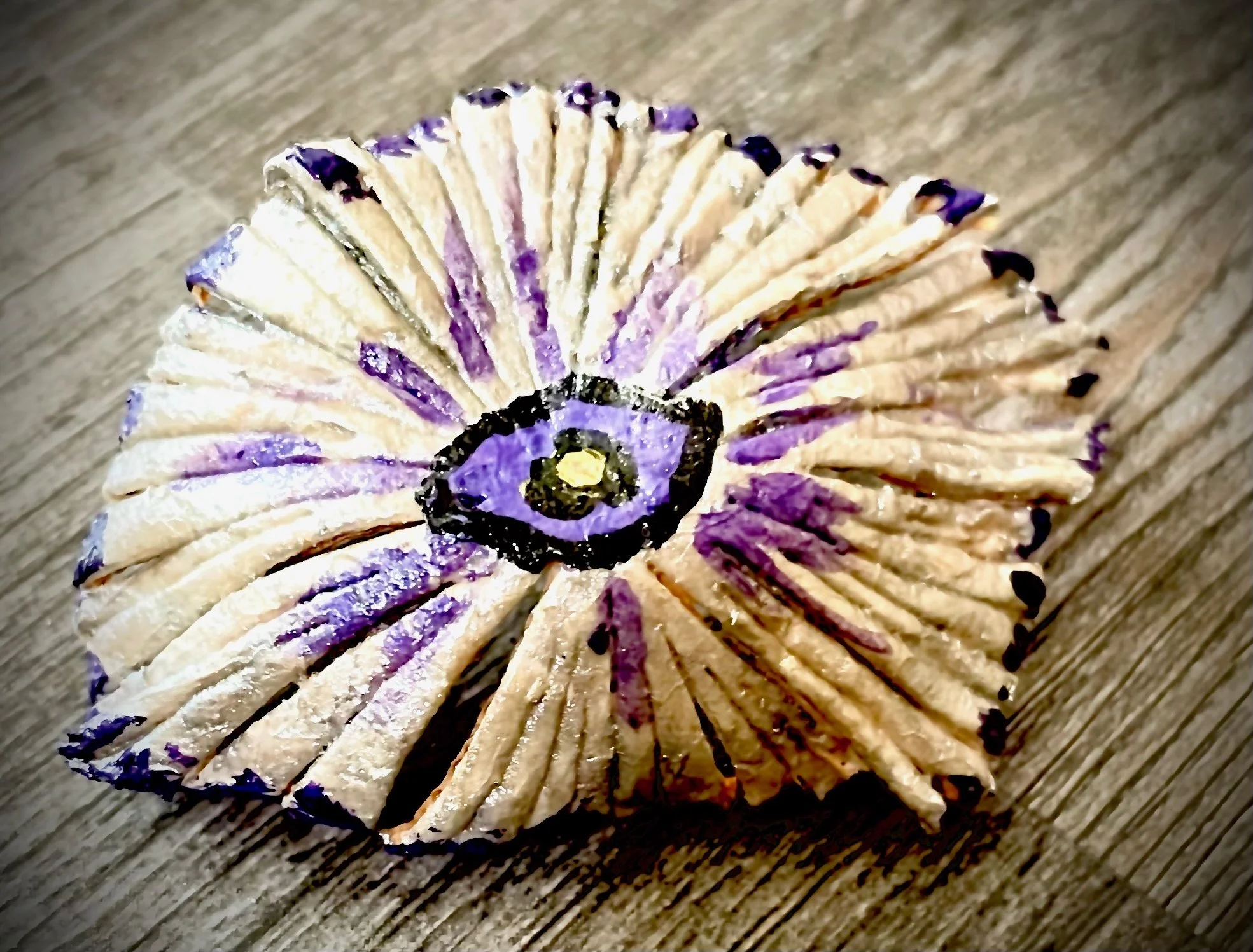 A spiraled decorative citrus rind with a purple and black design on a wooden surface.