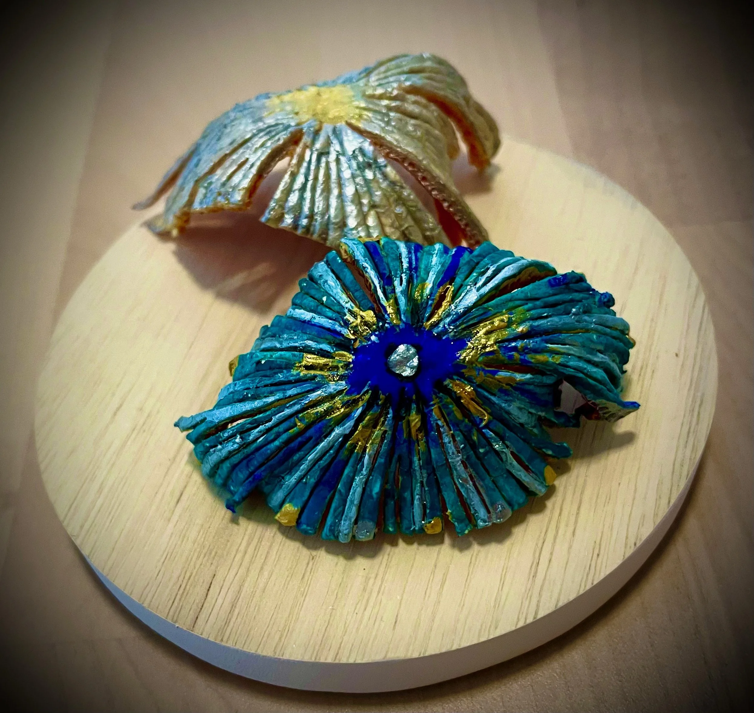 Colorful, textured citrus rind art piece resembling a sunburst on a light wooden surface.