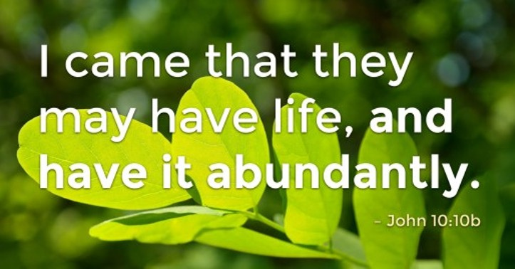 Close-up of green leaves with a Bible verse quote: 'I came that they may have life, and have it abundantly.' - John 10:10b, on a blurred green background.
