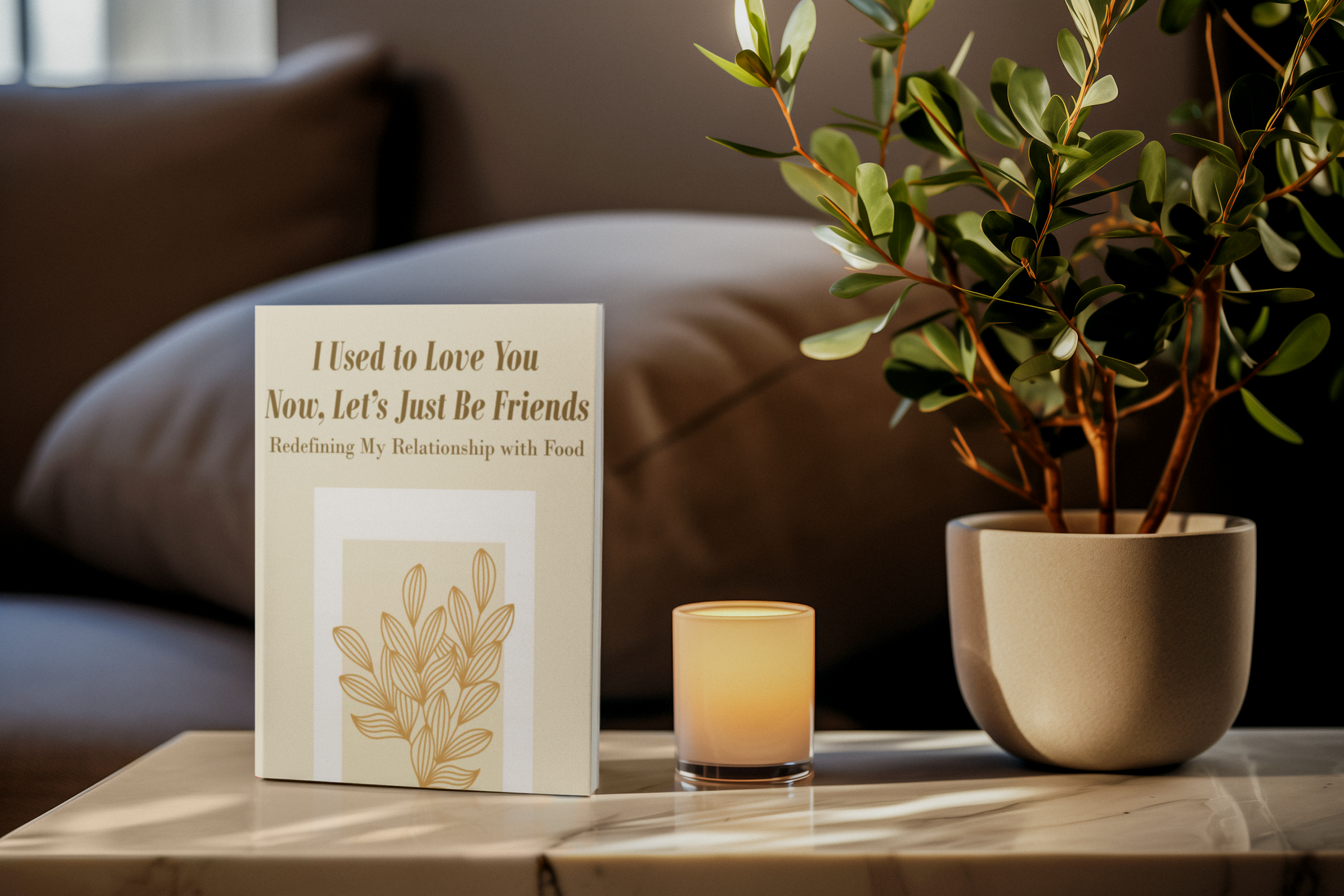 A potted green leafy plant on a table with a candle and a card that reads, 'I Used to Love You Now, Let's Just Be Friends. Redefining My Relationship with Food.' In the background, a blurred sofa and window are visible.