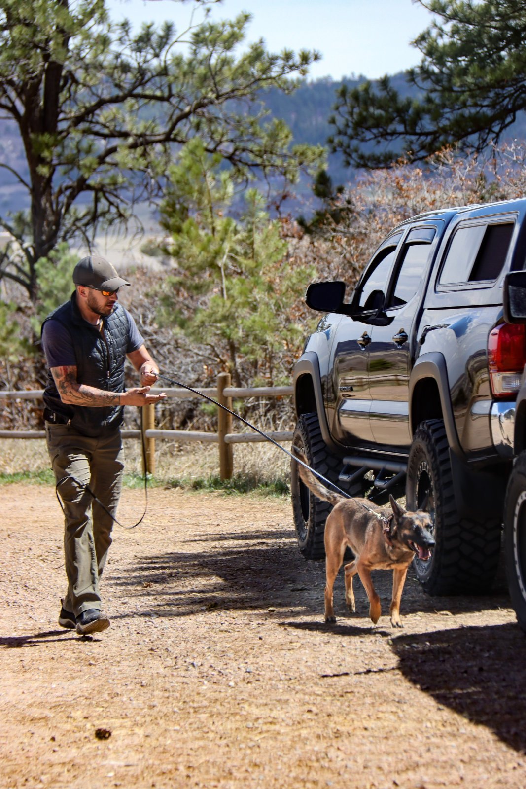 Mitch holding a dog’s leash beside a parked pickup truck.