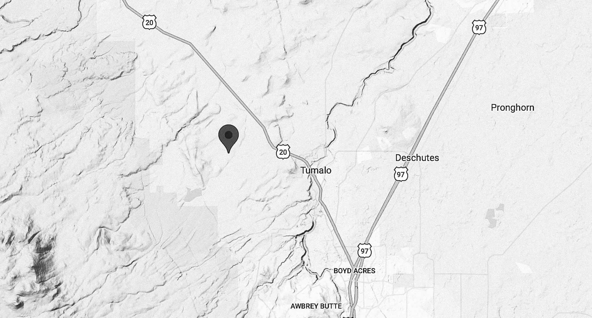 A grayscale map showing highways US 20 and US 97 near Tumalo, Deschutes, and Boyd Acres, with a pin marking a specific location in a mountainous area west of Tumalo and Deschutes, Oregon.