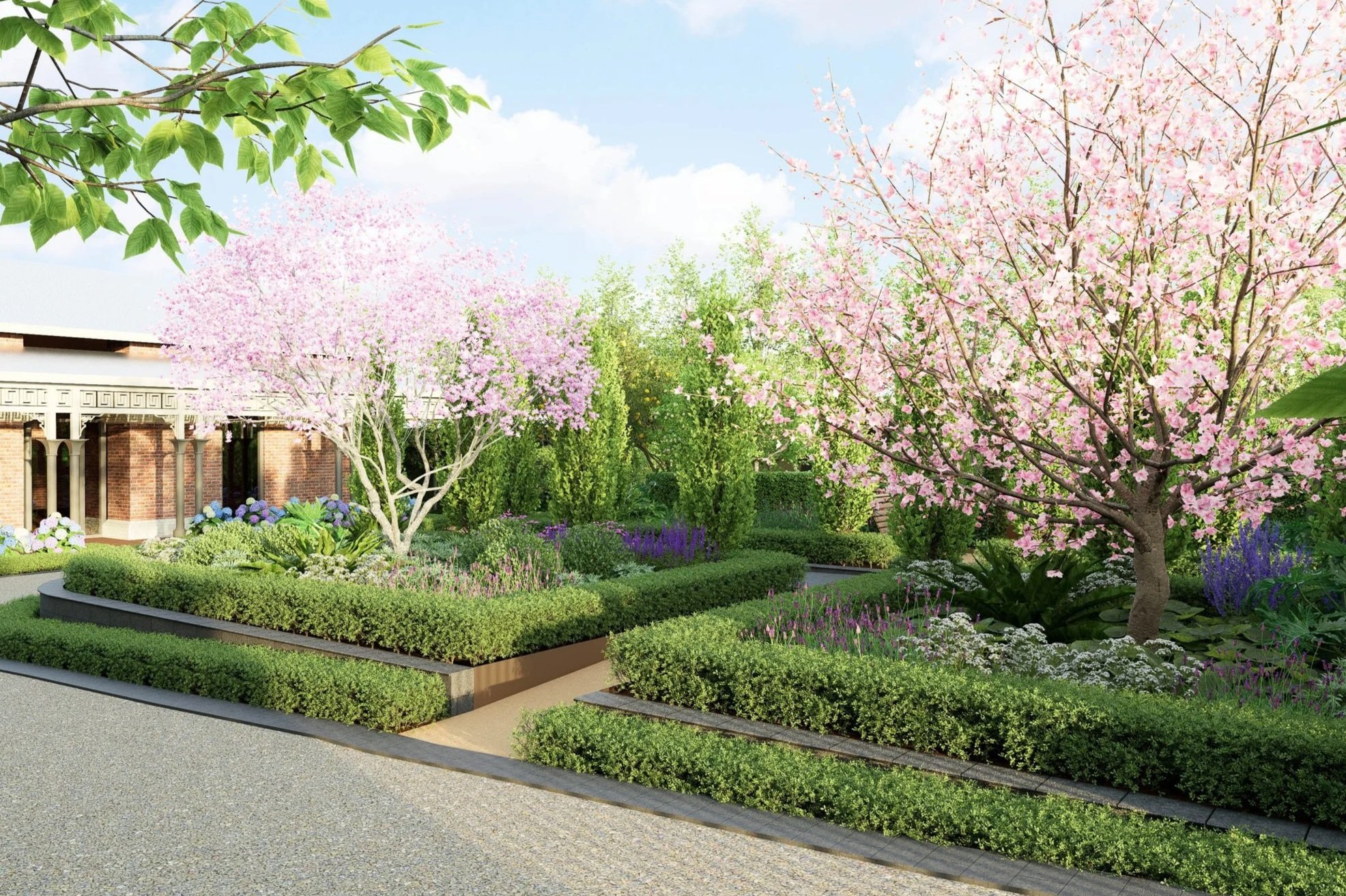 Garden with blooming pink cherry blossom trees, various green shrubs, and colorful flowers, with a brick building and blue sky in the background.