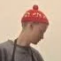 A person wearing a red beanie and gray hoodie.