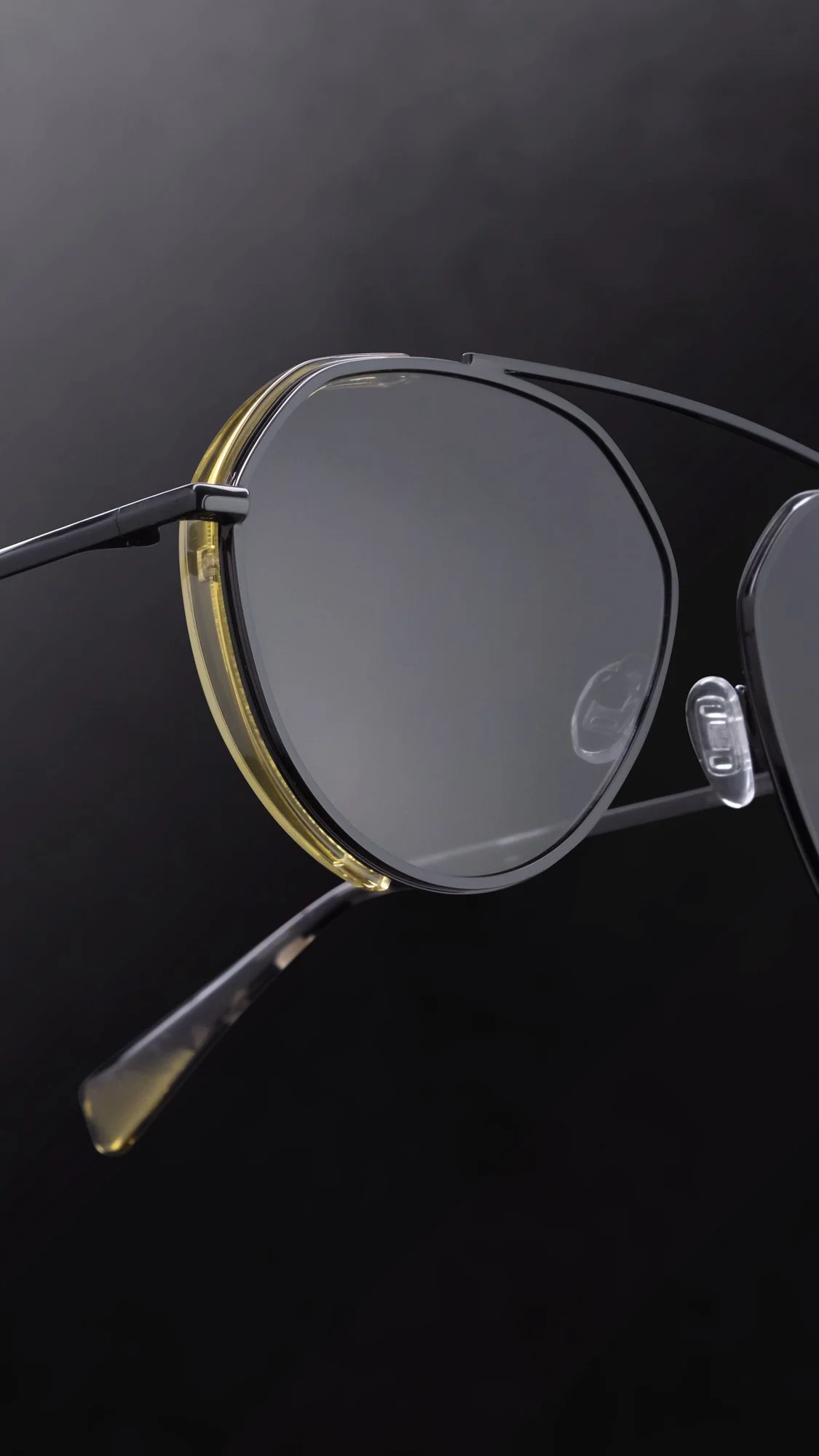 Close-up of a pair of round metal sunglasses , set against a dark background.