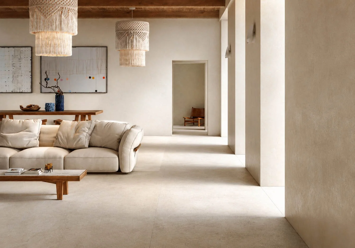 Intérieur épuré d'un salon avec un canapé blanc en velours, une table en bois, des œuvres d'art abstraites sur le mur, et des lampes en macramé suspendues au plafond.