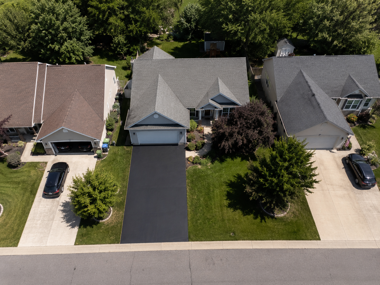 Aerial view of three suburban houses with middle driveway recoated