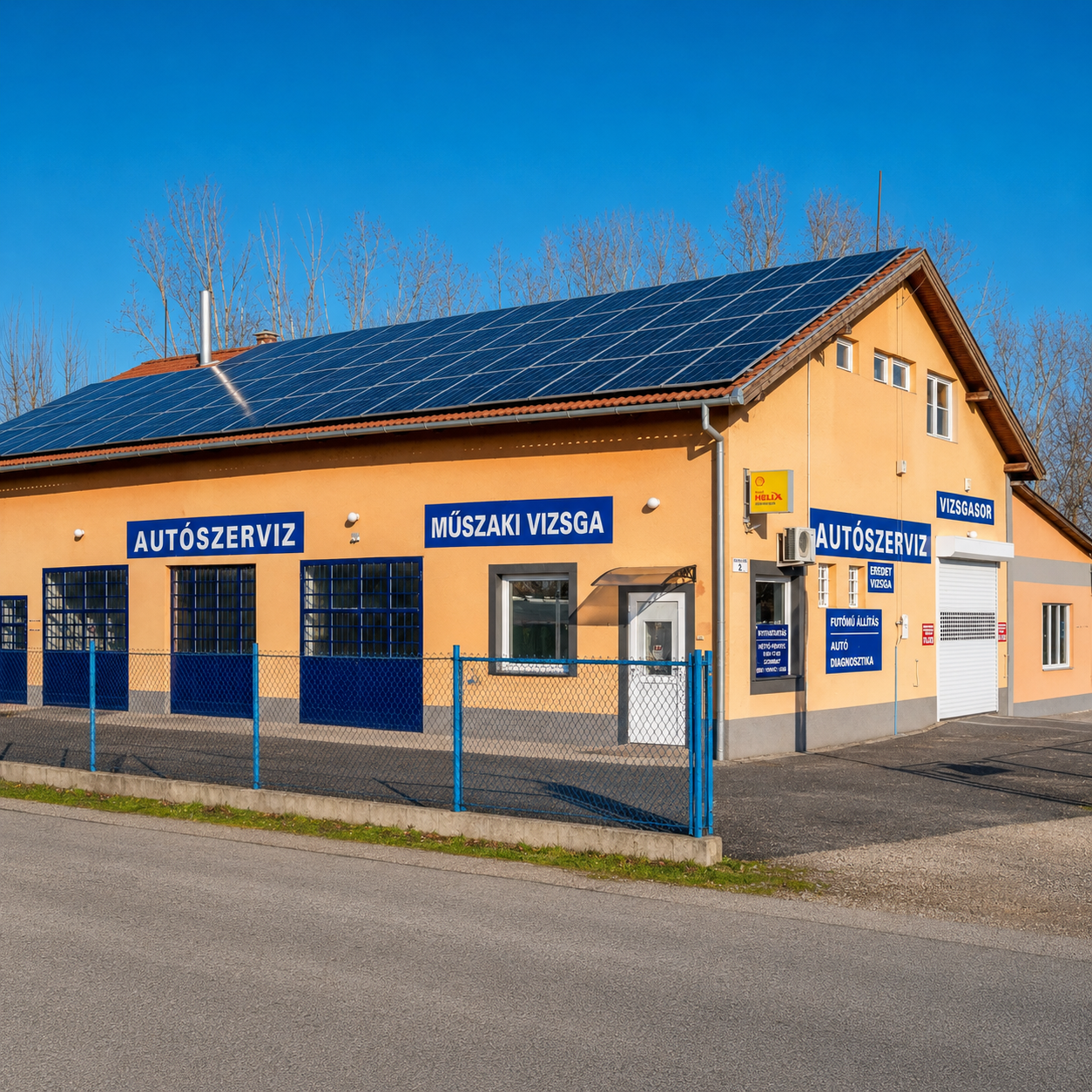 Orange building with blue signs in Hungarian, including 'Autószerviz' and 'Műszaki Vizsga', with solar panels on roof and a blue fence in front, under a clear blue sky.