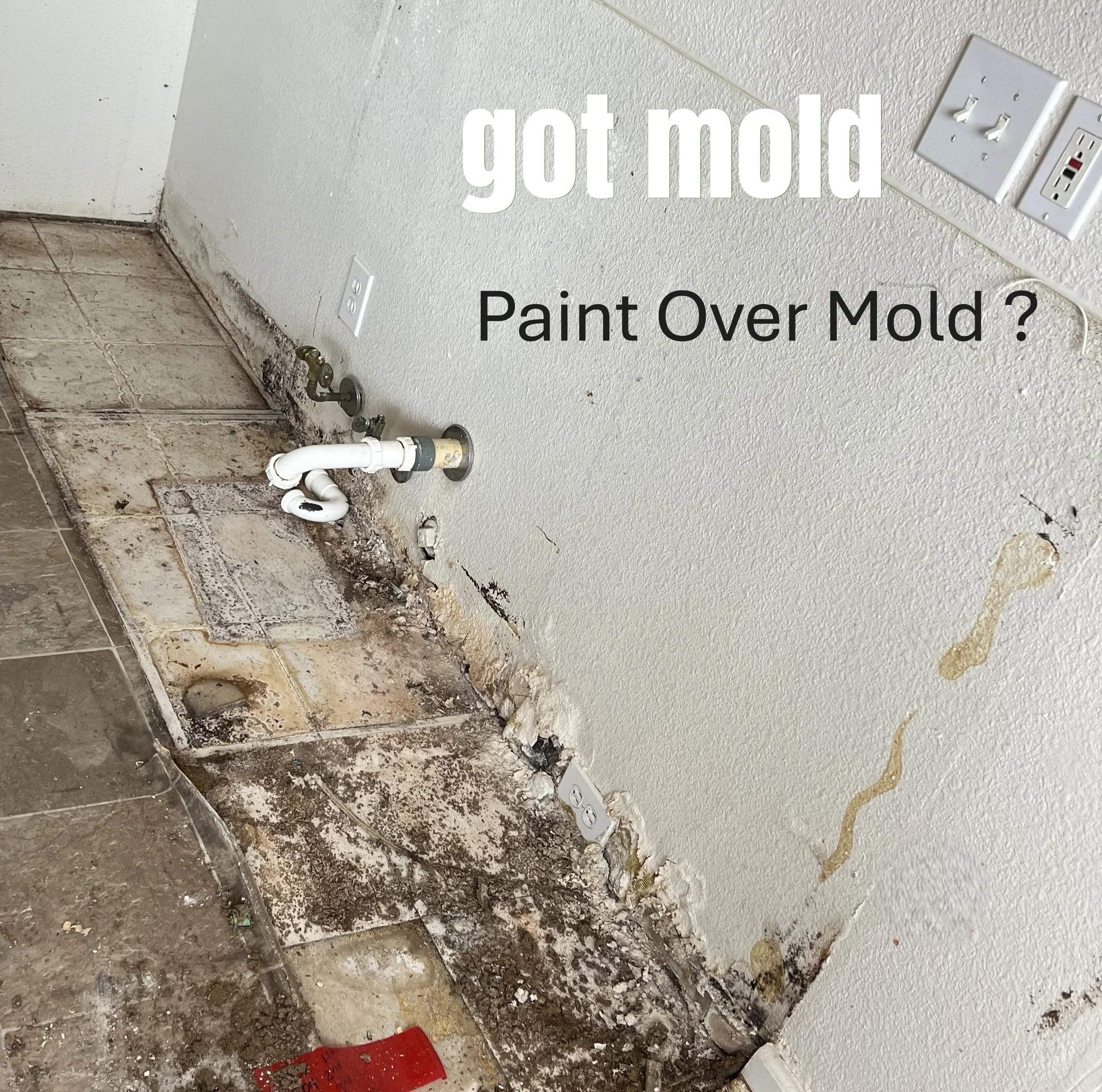 View of a renovation area showing a wall with missing baseboards, exposed piping, and electrical outlets, with debris and a red object on the floor.