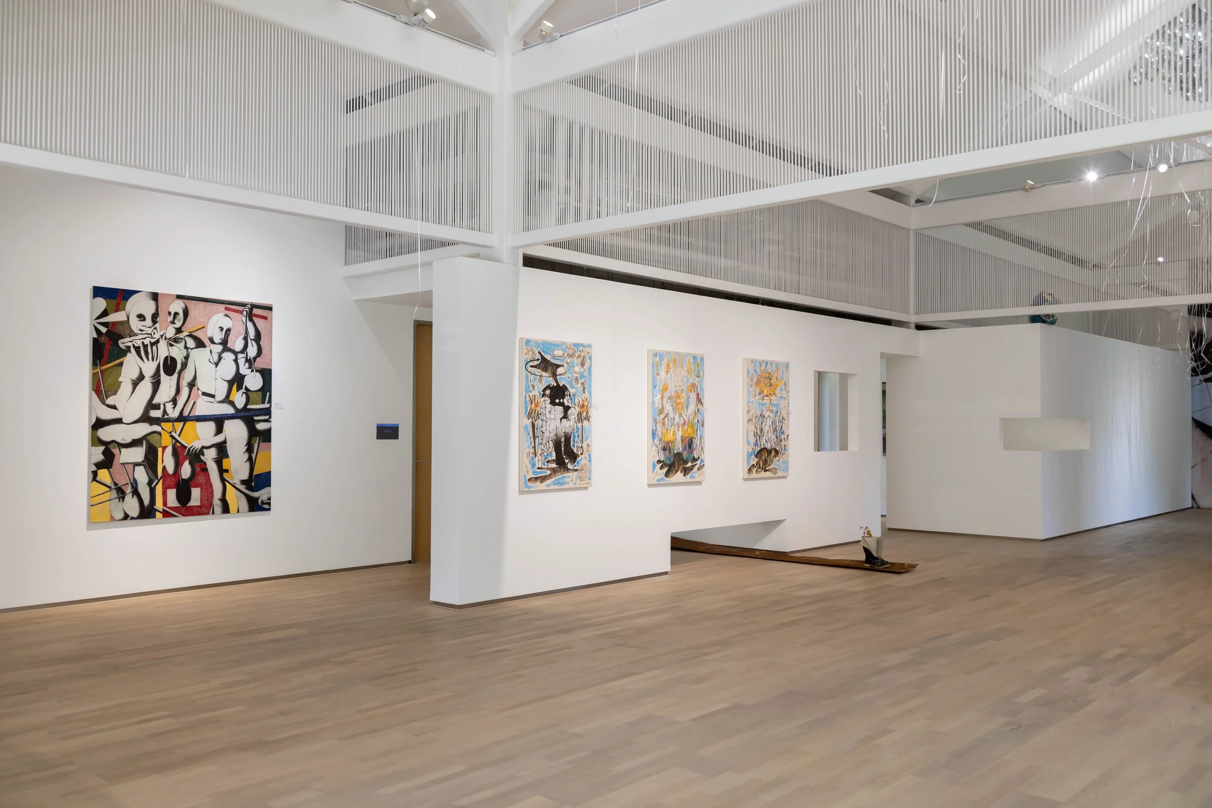 Gallery with white walls and wooden floor, featuring colorful abstract paintings, and a ceiling with white slats and track lighting.