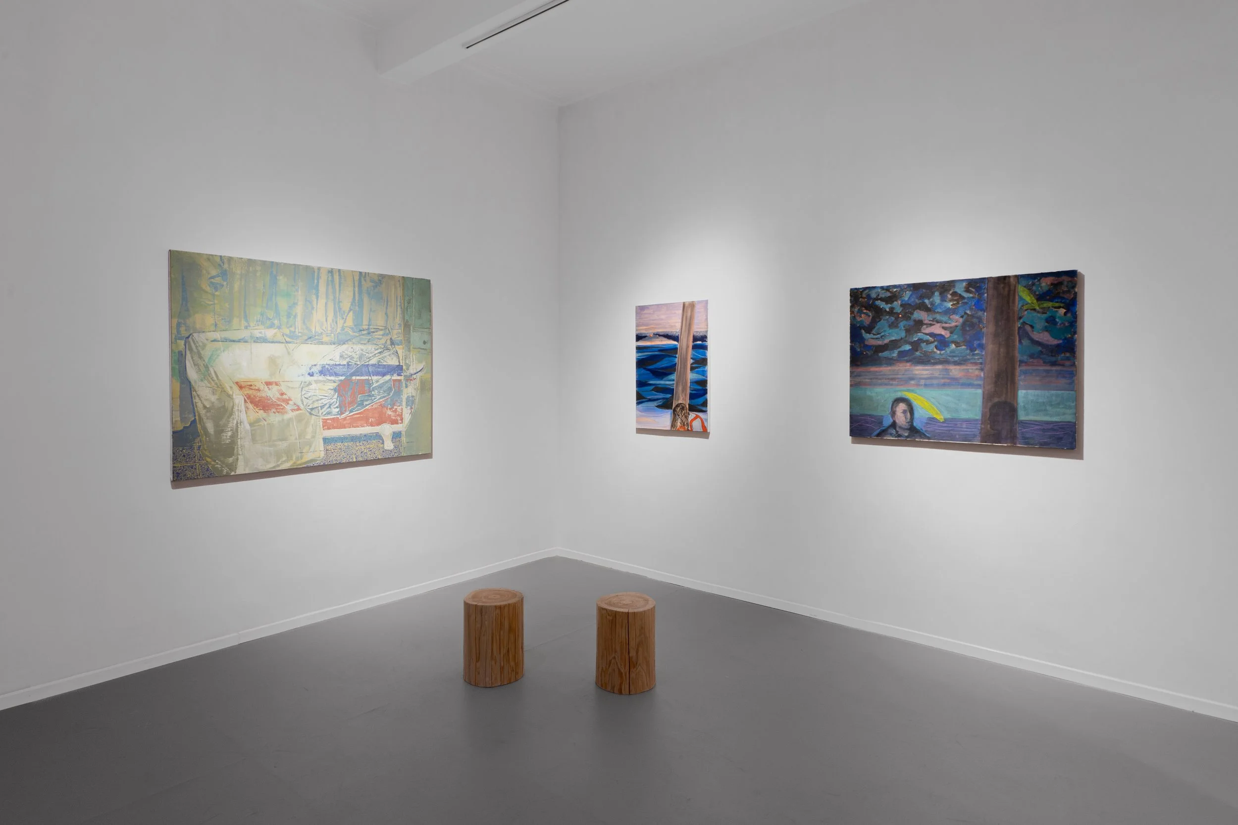 An art gallery with white walls displaying three paintings. Two wooden stools are situated in front of the artworks on a gray floor.