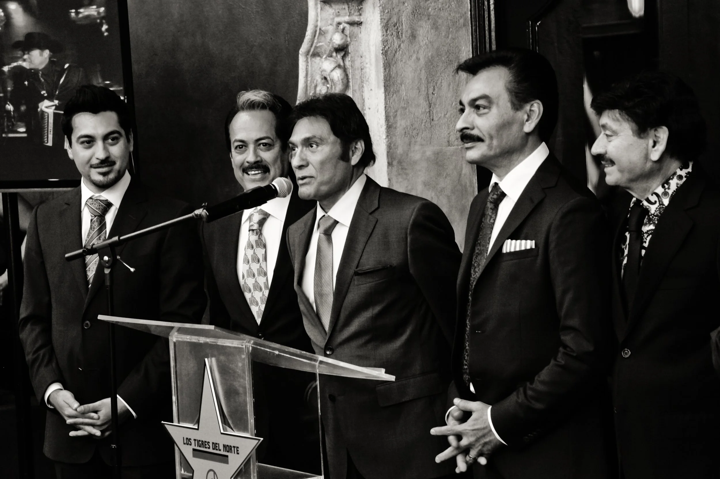Los Tigres del Norte receiving a lifetime achievement award in Los Angeles. Black-and-white documentary photograph capturing members of the iconic Norteño group during an award ceremony honoring their cultural and musical legacy.