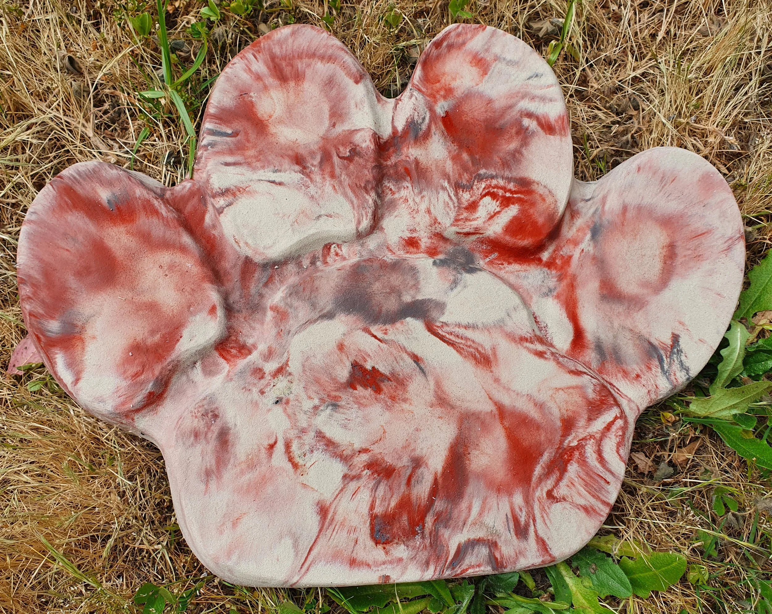Marbled concrete red and white paw print garden ornament.