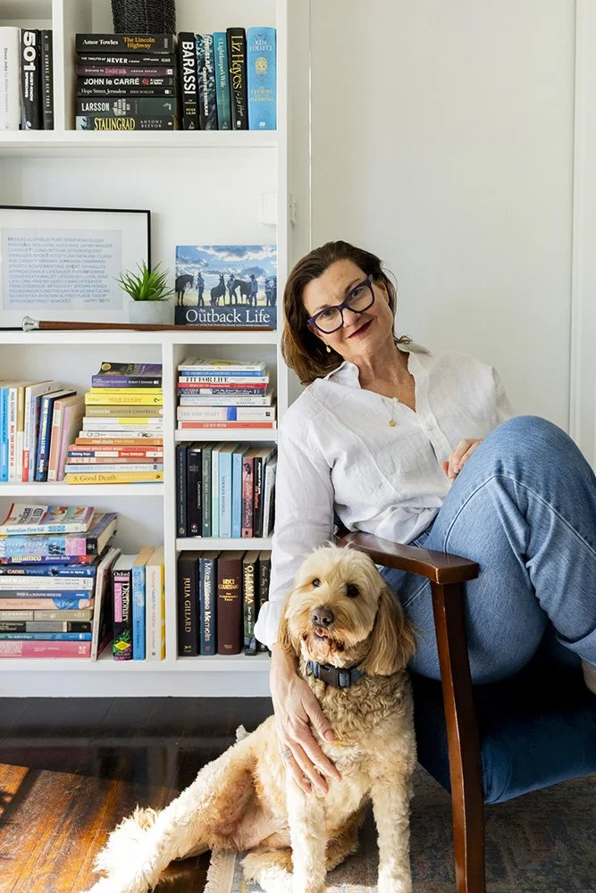 Narelle in front of a bookcase with her dog
