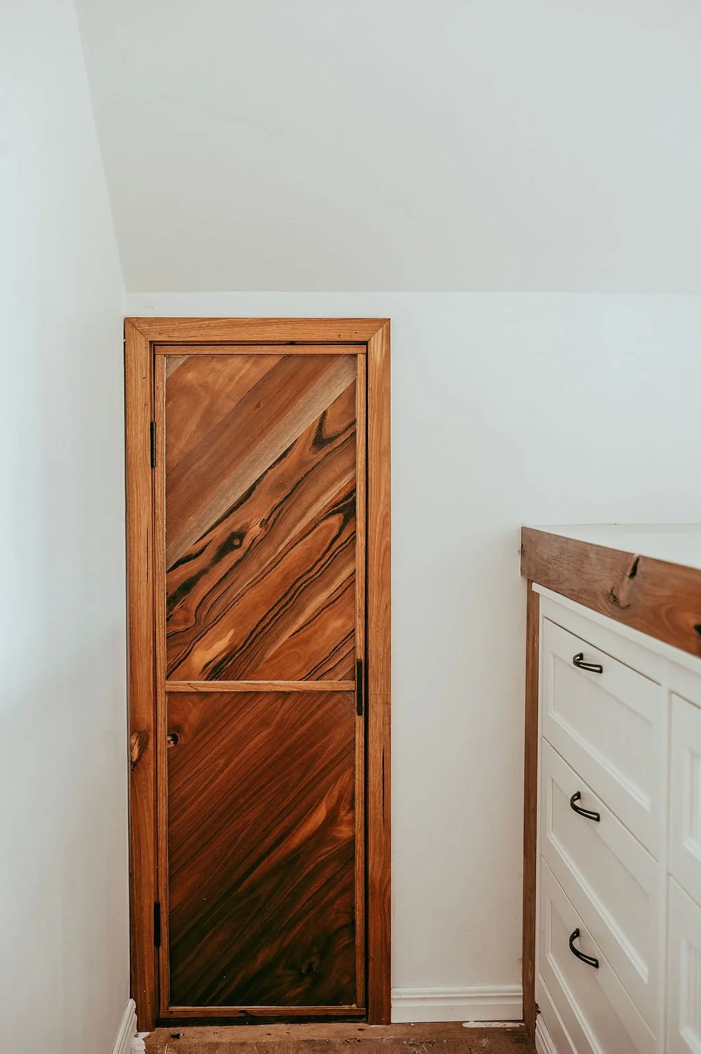 Interior corner view with a wooden door and a white dresser.