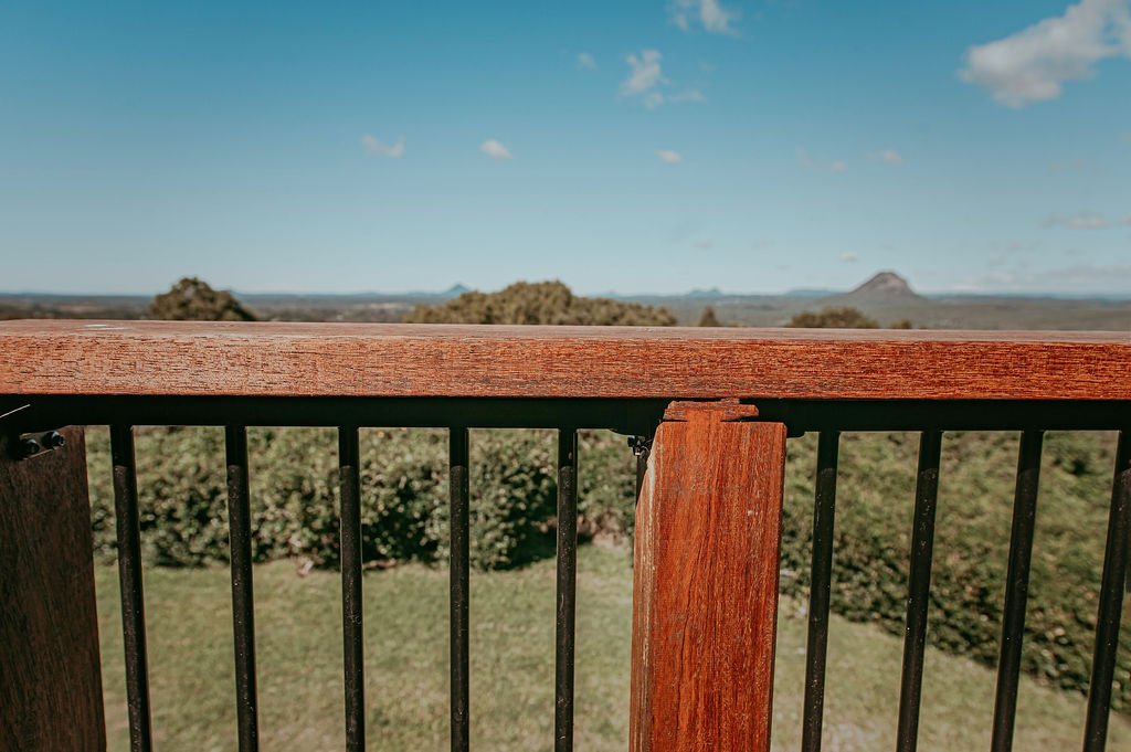 View of distant mountainous landscape with a wooden railing in the foreground.