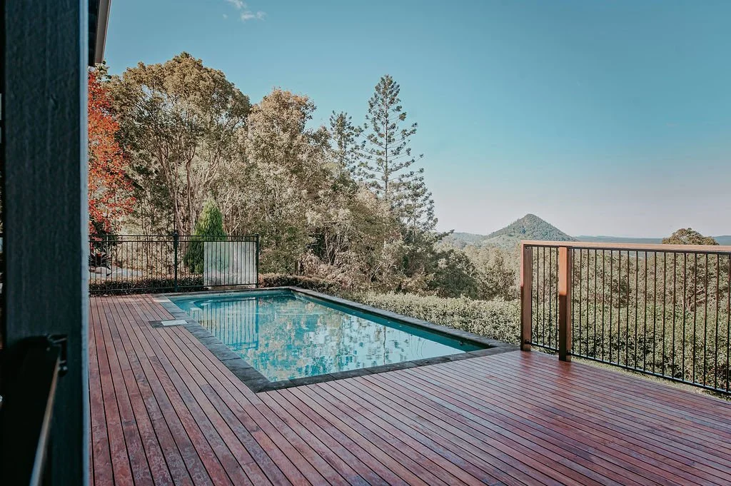 A house balcony with a swimming pool and a scenic mountain view.