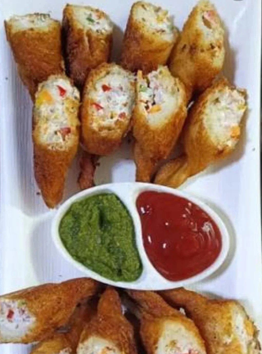 Fried spring rolls with green and red dipping sauces.