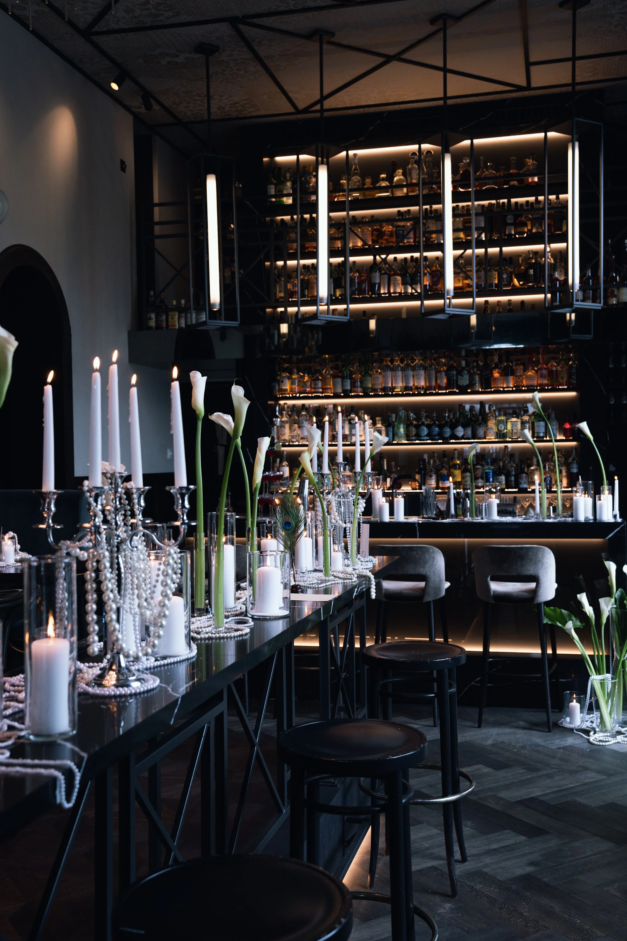 Ein stilvoll dekorierter Bar- und Essbereich mit Kerzen, weißen Blumen und Perlenneklace in einem modernen Restaurant.