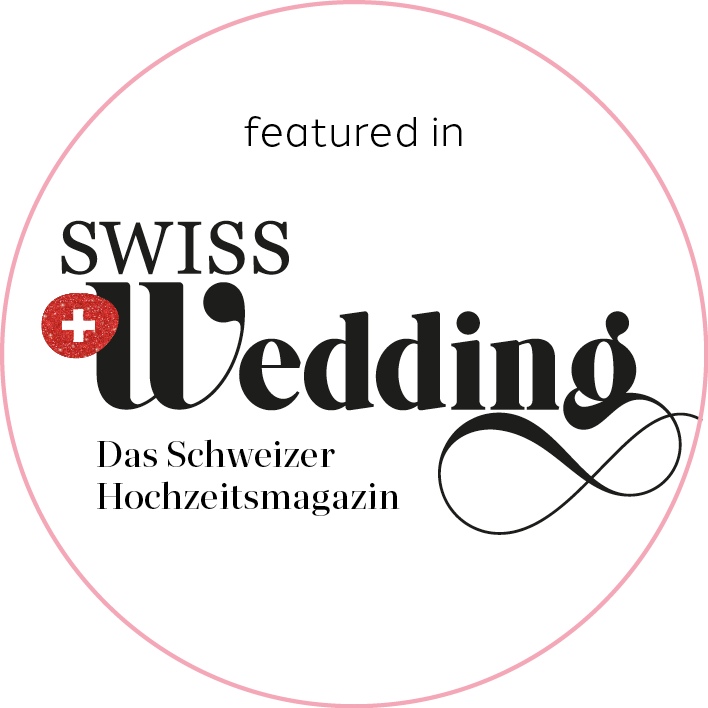 Logo des Schweizer Hochzeitsmagazins 'Swiss Wedding', das in einer kreisförmigen Gestaltung mit schwarzer, roter und weißer Farbgestaltung präsentiert wird.