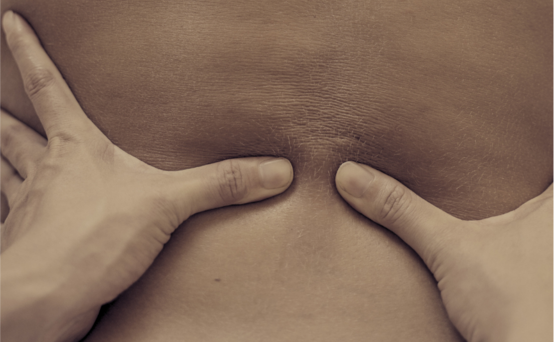 Close-up of a person's bare back with hands providing massage / bodywork.
