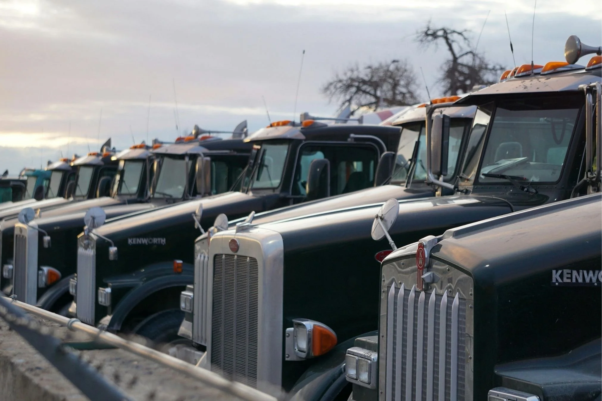 Fleet of commercial trucks parked in formation, showcasing risk management services from a commercial truck insurance broker.