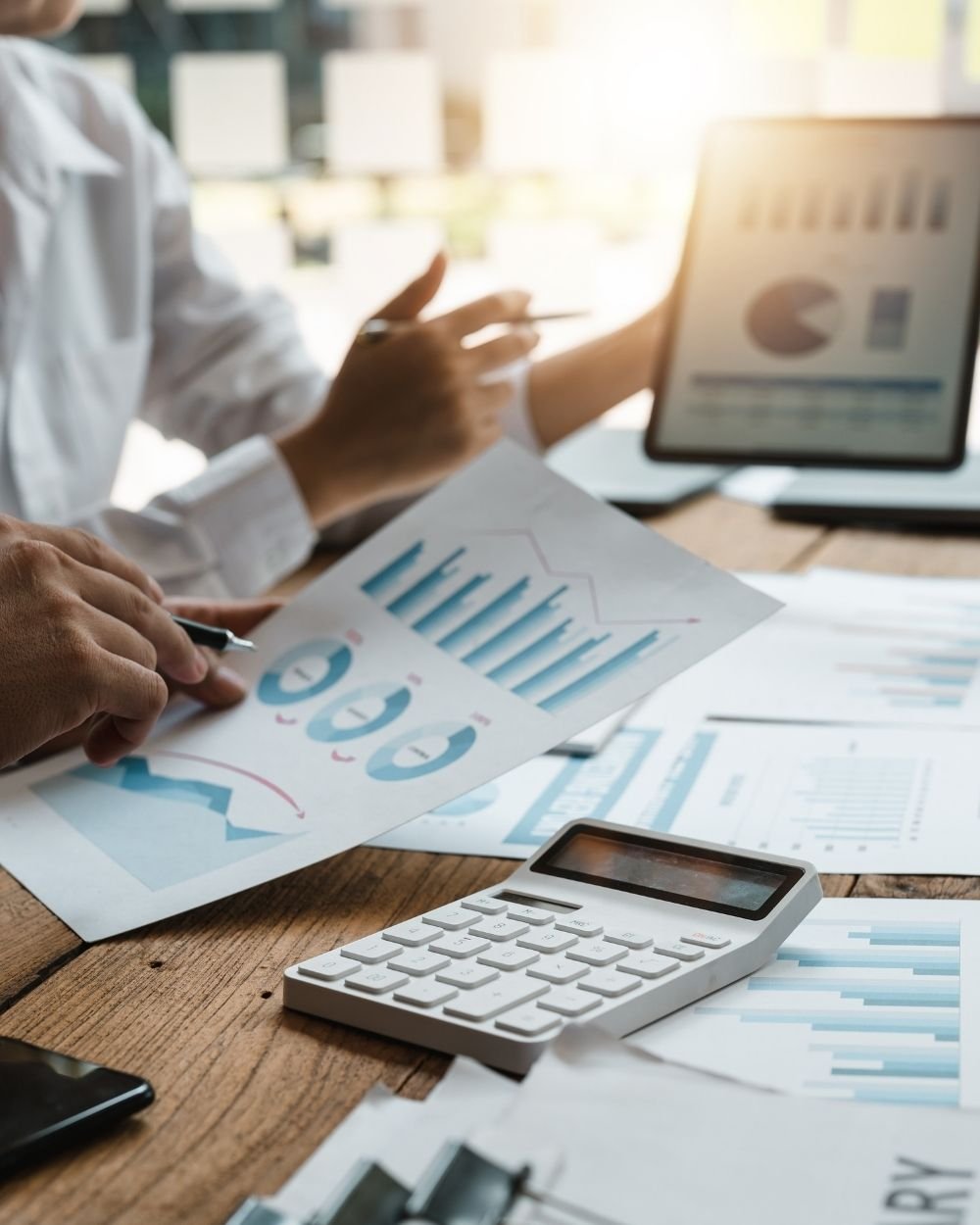 Business professionals analyzing reports and expenses to estimate fleet insurance costs and manage transportation risk.