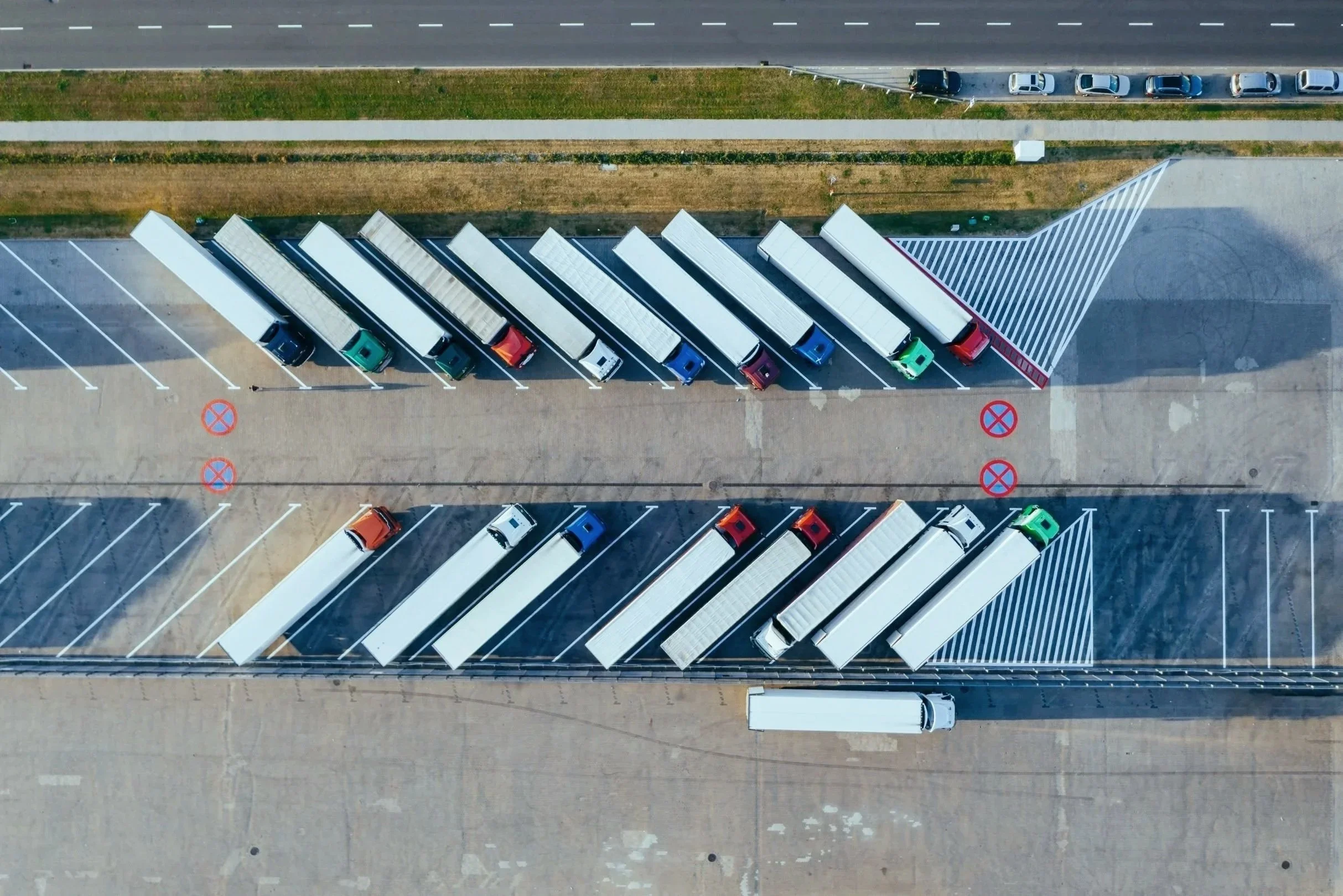 Aerial view of trailers and trucks in a logistics facility, highlighting customized fleet insurance solutions for transportation companies.