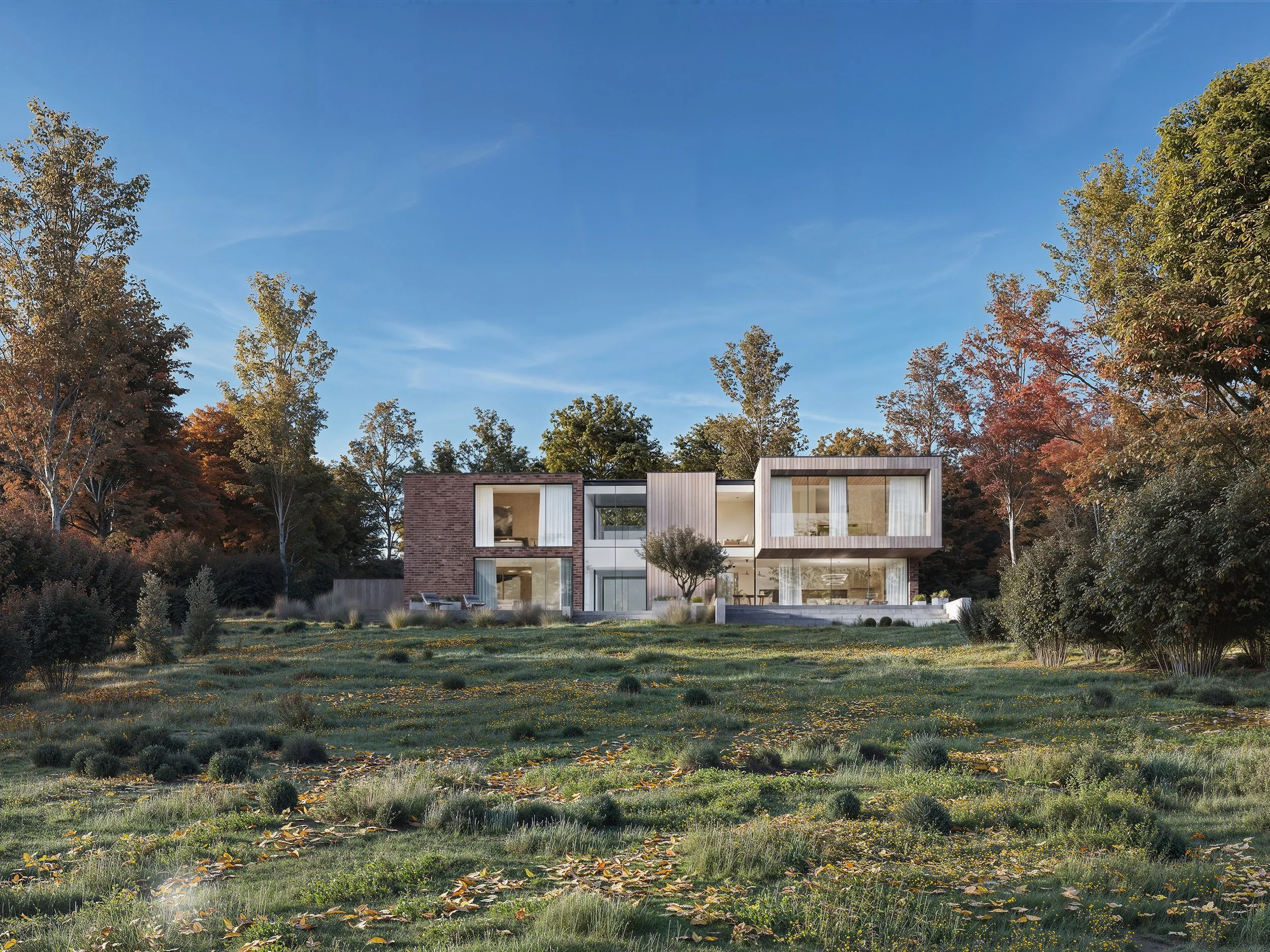 Modern house with large windows and flat roof, surrounded by trees with autumn foliage, under a clear blue sky.