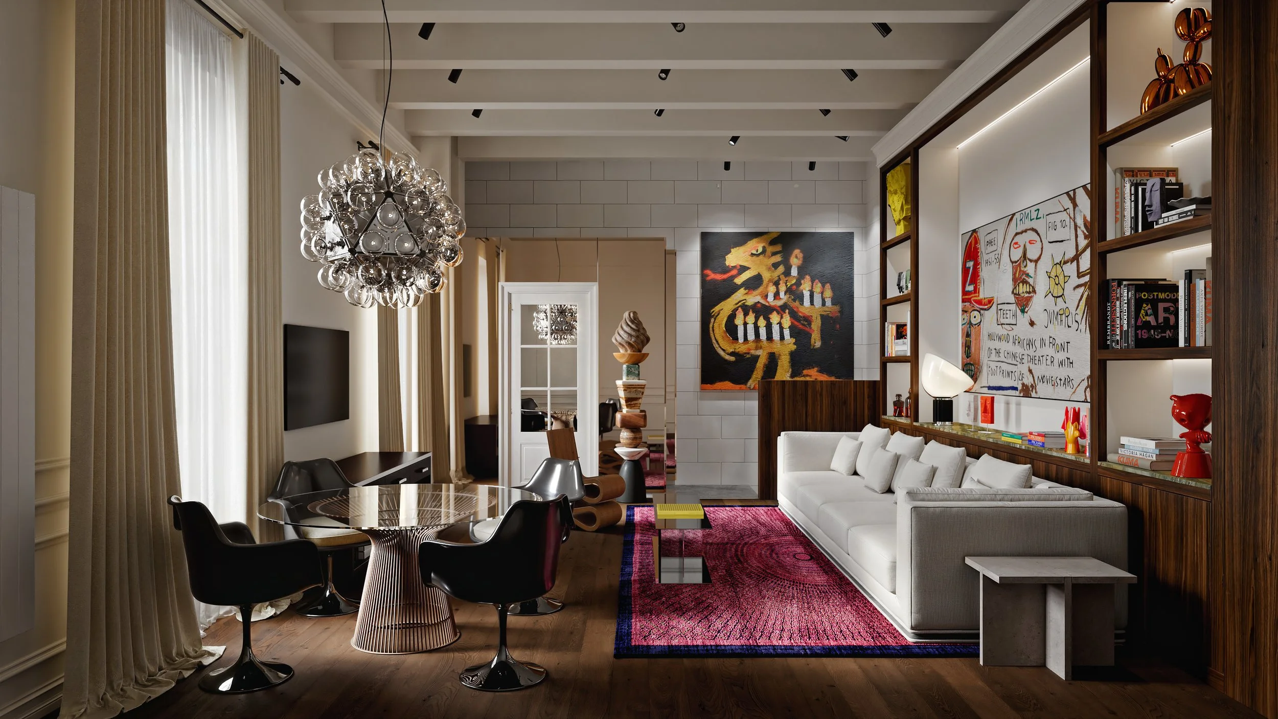 Modern living room with a white couch, colorful artwork, bookshelf, and round dining table with black chairs, illuminated by a statement chandelier.